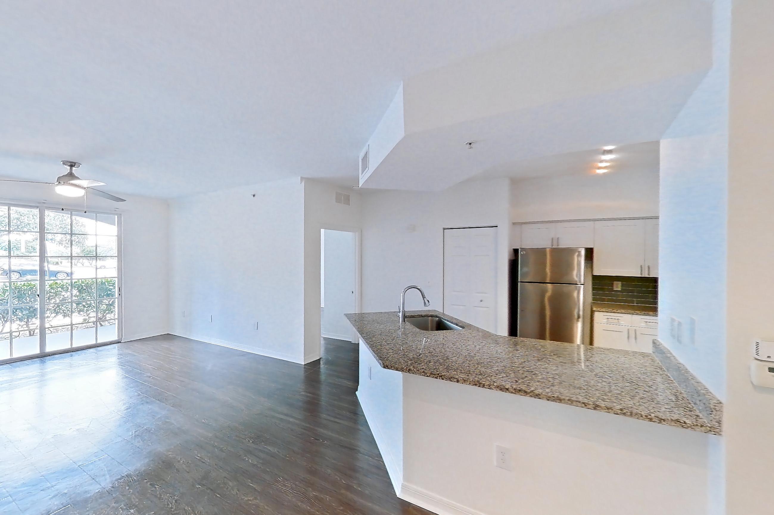Living space with dark wood-finish flooring, refrigerator, and stainless steel appliances, Apartment 08-110 at Solano at Miramar