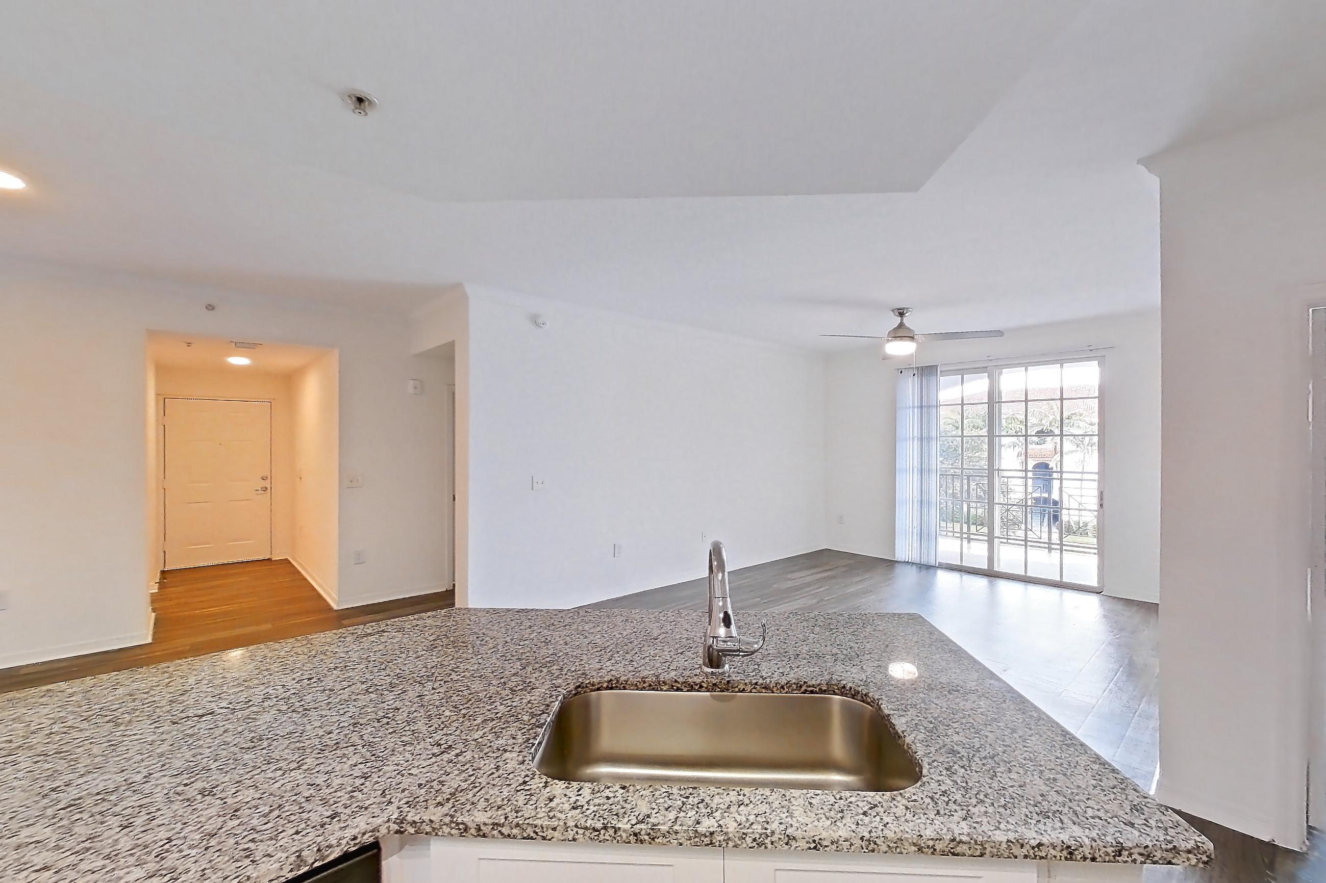 Kitchen with dark wood-finish flooring, dishwasher, electric range, light stone countertops, light wood-finish flooring, microwave, oven/range, refrigerator, and stainless steel appliances, Apartment 08-310 at Solano at Miramar