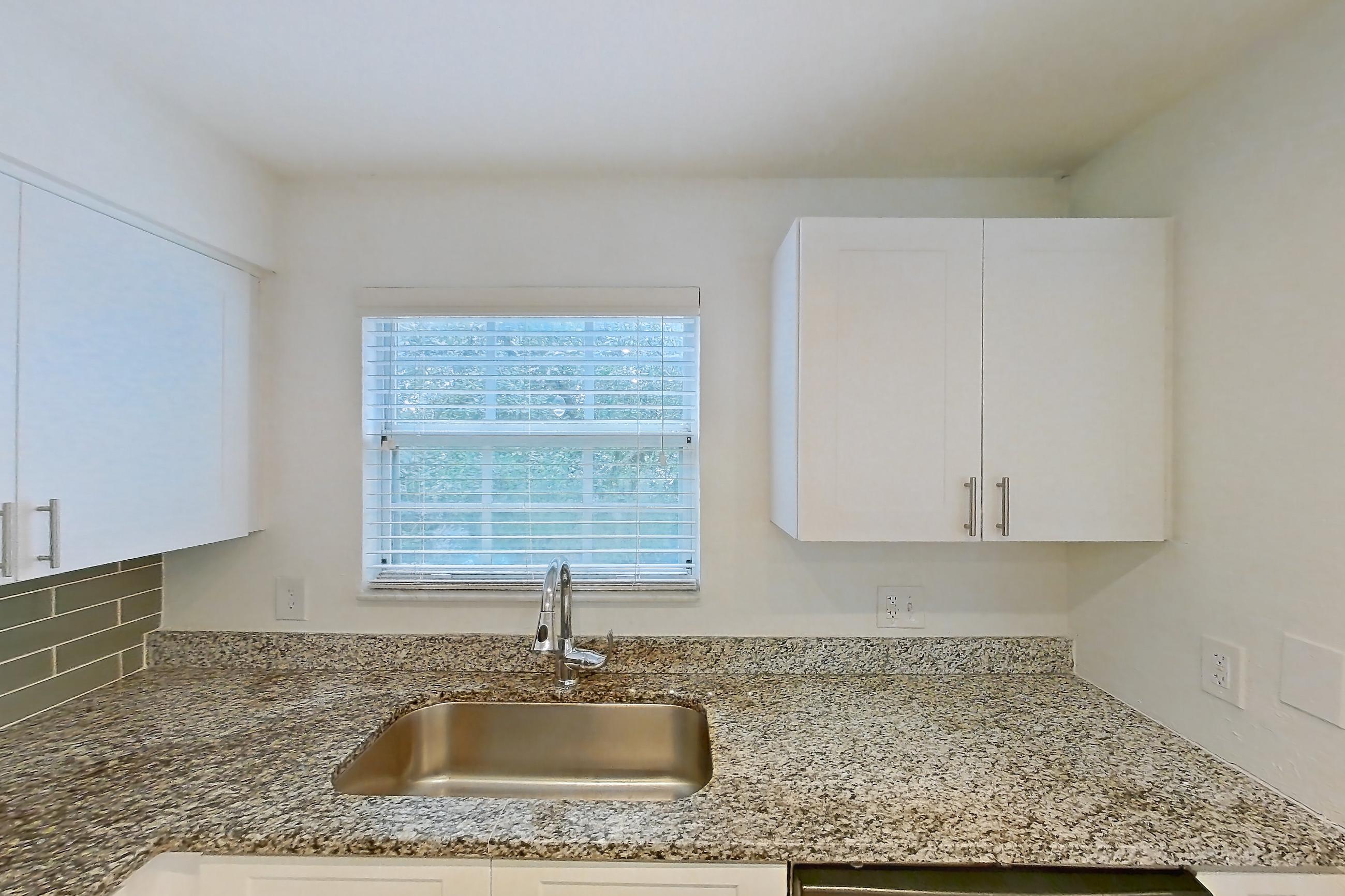 Kitchen with dark stone countertops, dishwasher, electric range, light countertops, light stone countertops, light wood-finish flooring, microwave, oven/range, and stainless steel appliances, Apartment 16-02573 at Solano at Miramar