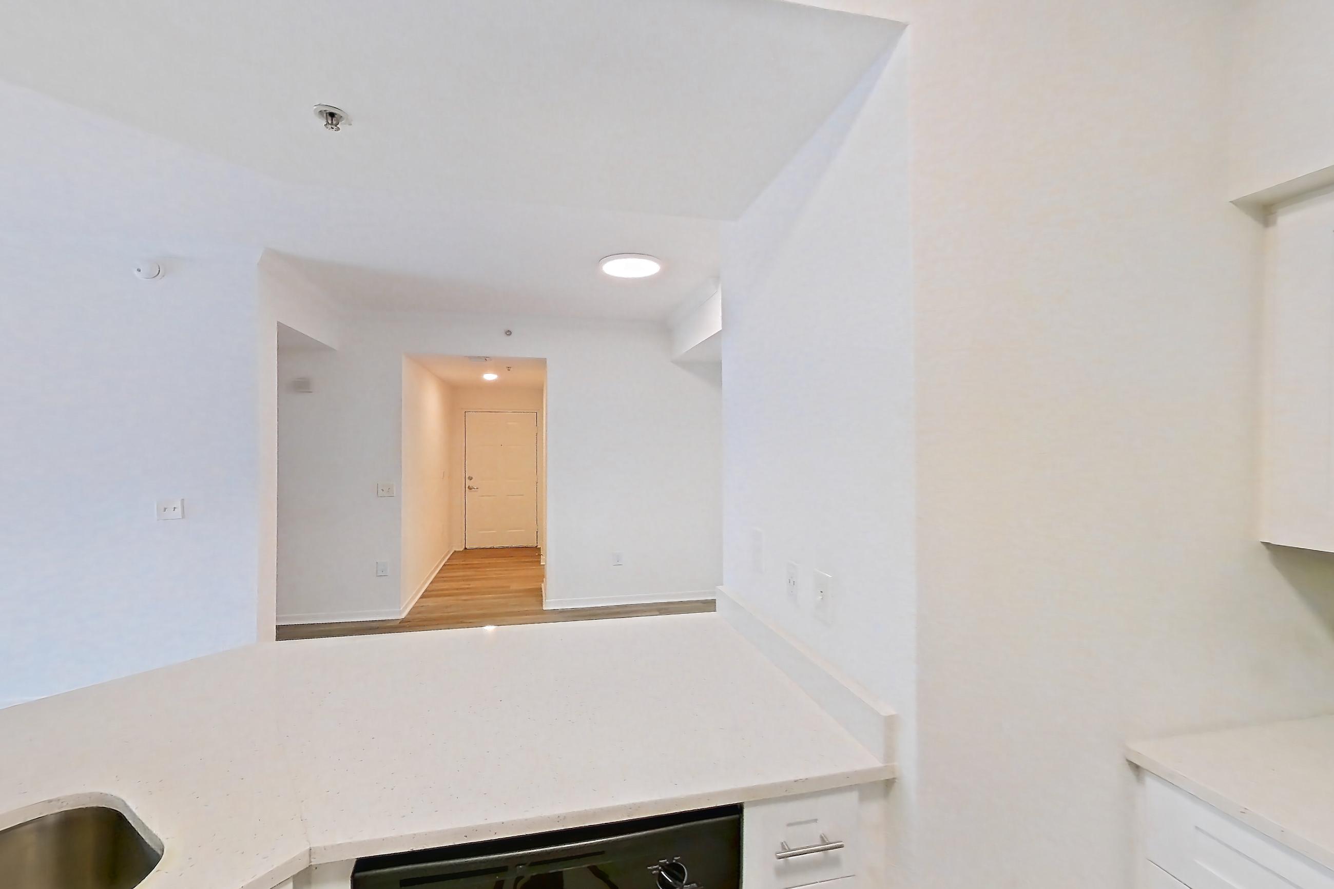 Kitchen with dishwasher, electric range, light countertops, light stone countertops, light wood-finish flooring, microwave, oven/range, refrigerator, and stainless steel appliances, Apartment 03-304 at Solano at Miramar