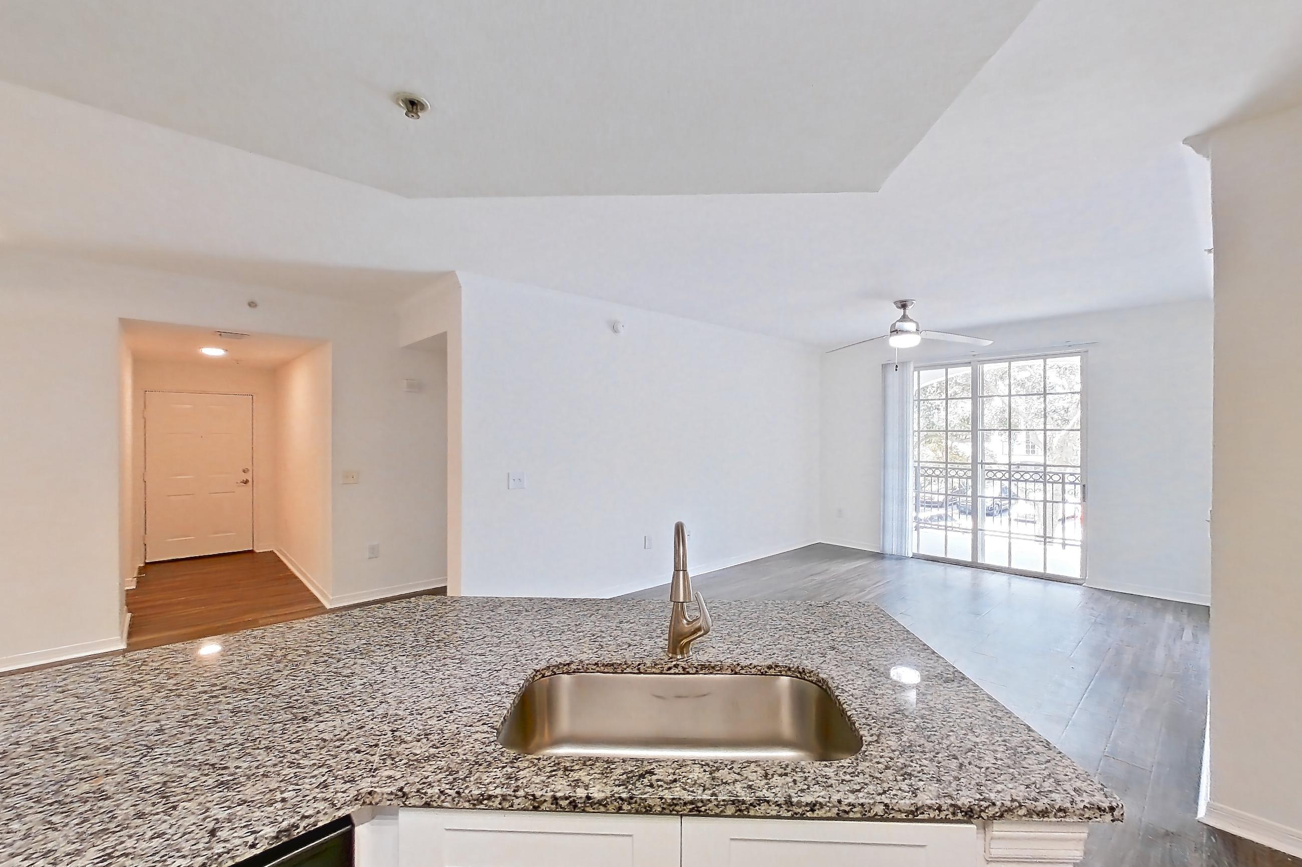 Kitchen with dark wood-finish flooring, dishwasher, electric range, light stone countertops, microwave, oven/range, refrigerator, and stainless steel appliances, Apartment 04-205 at Solano at Miramar