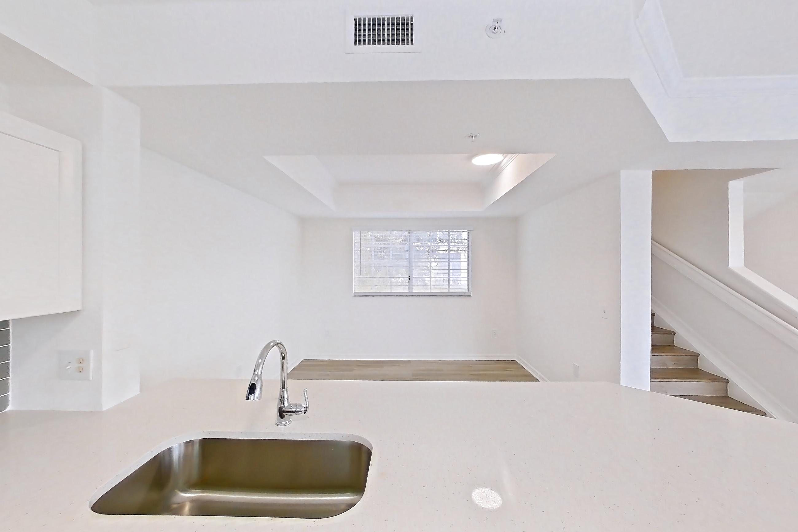 Kitchen with dishwasher, electric range, light countertops, light stone countertops, light wood-finish flooring, microwave, oven/range, refrigerator, and stainless steel appliances, Apartment 14-11734 at Solano at Miramar
