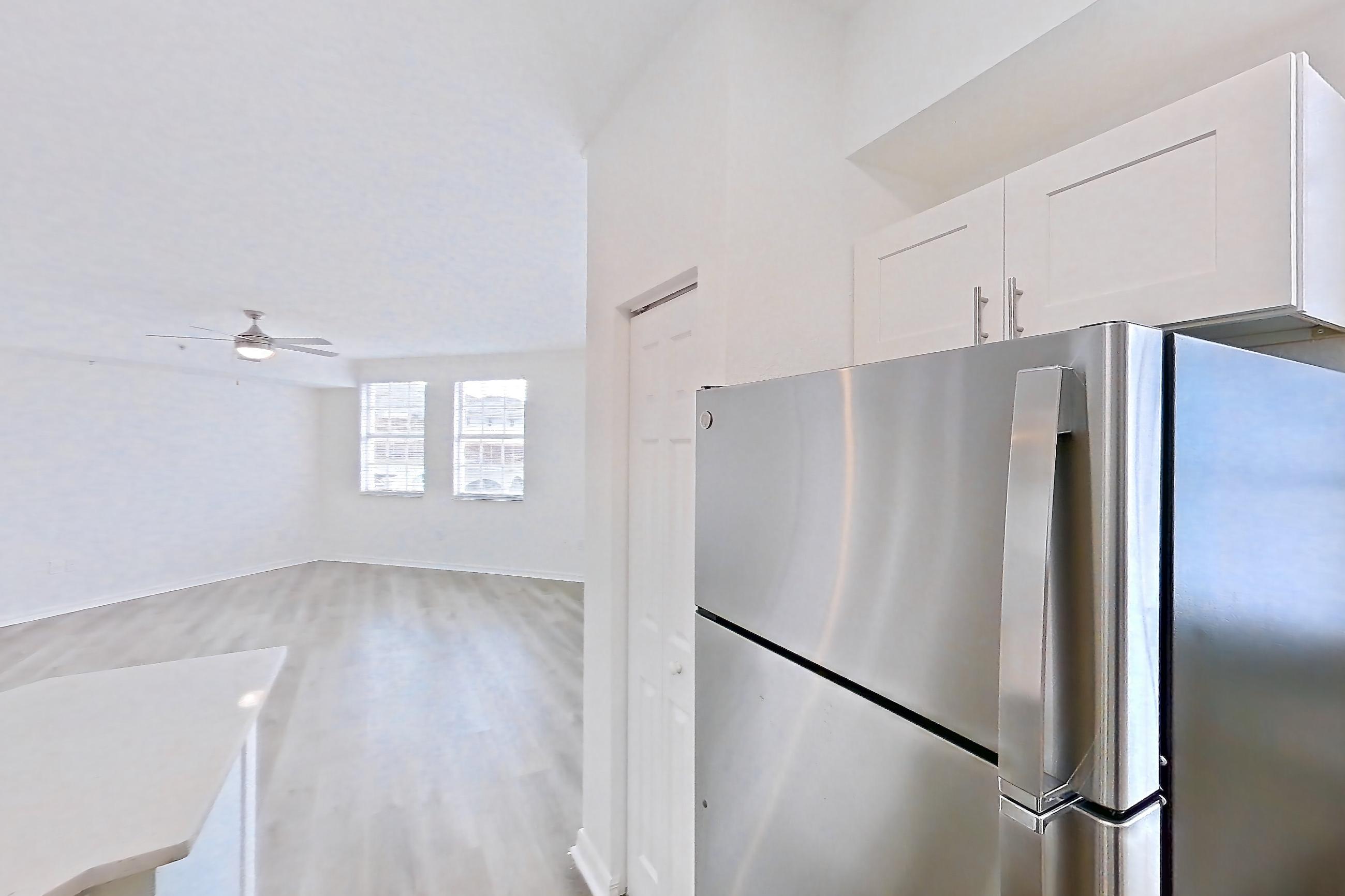 Kitchen with dishwasher, electric range, light countertops, light stone countertops, light wood-finish flooring, microwave, oven/range, refrigerator, and stainless steel appliances, Apartment 14-11734 at Solano at Miramar