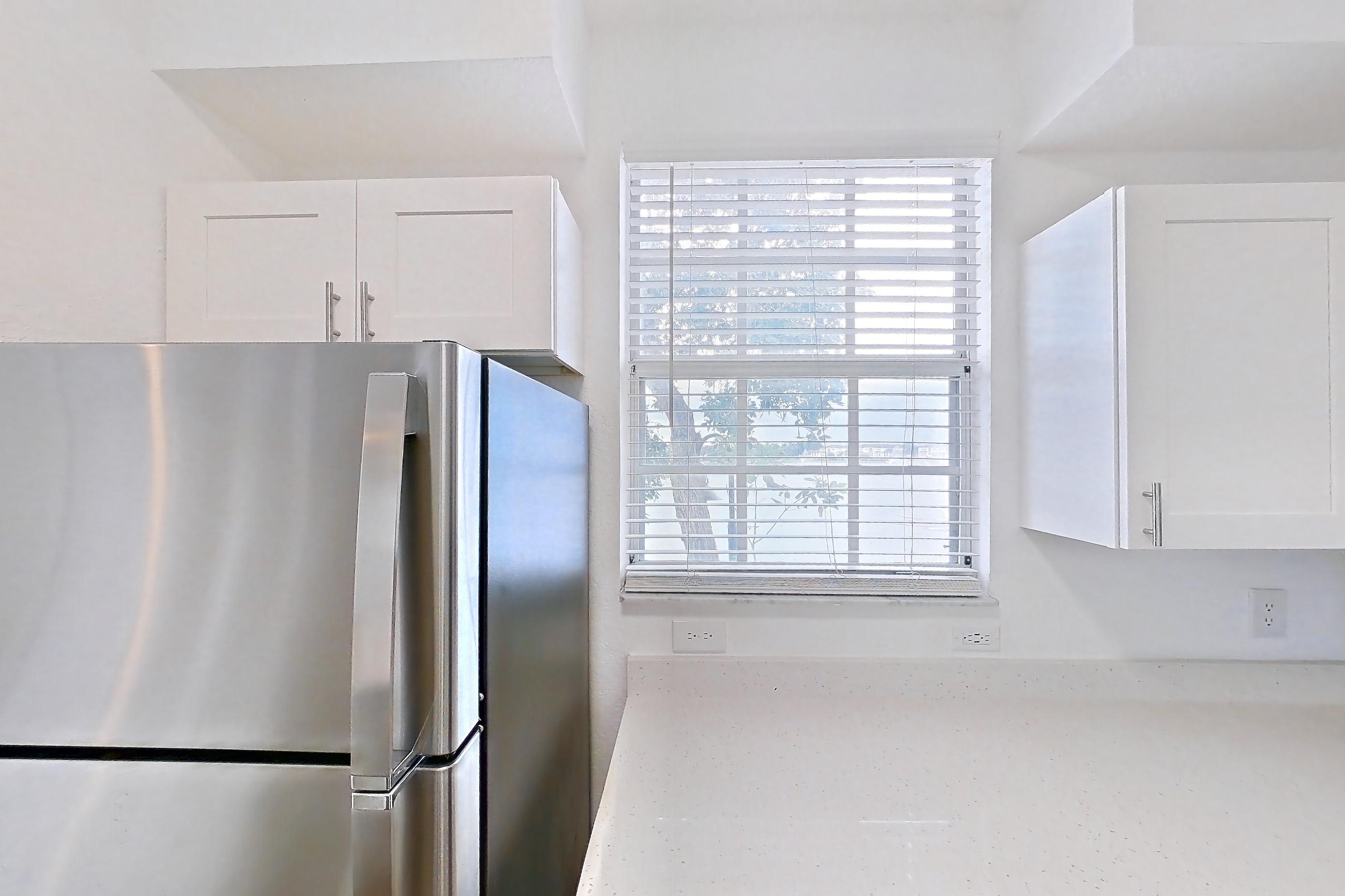 Kitchen with dishwasher, electric range, light countertops, light stone countertops, light wood-finish flooring, microwave, oven/range, refrigerator, and stainless steel appliances, Apartment 14-11734 at Solano at Miramar