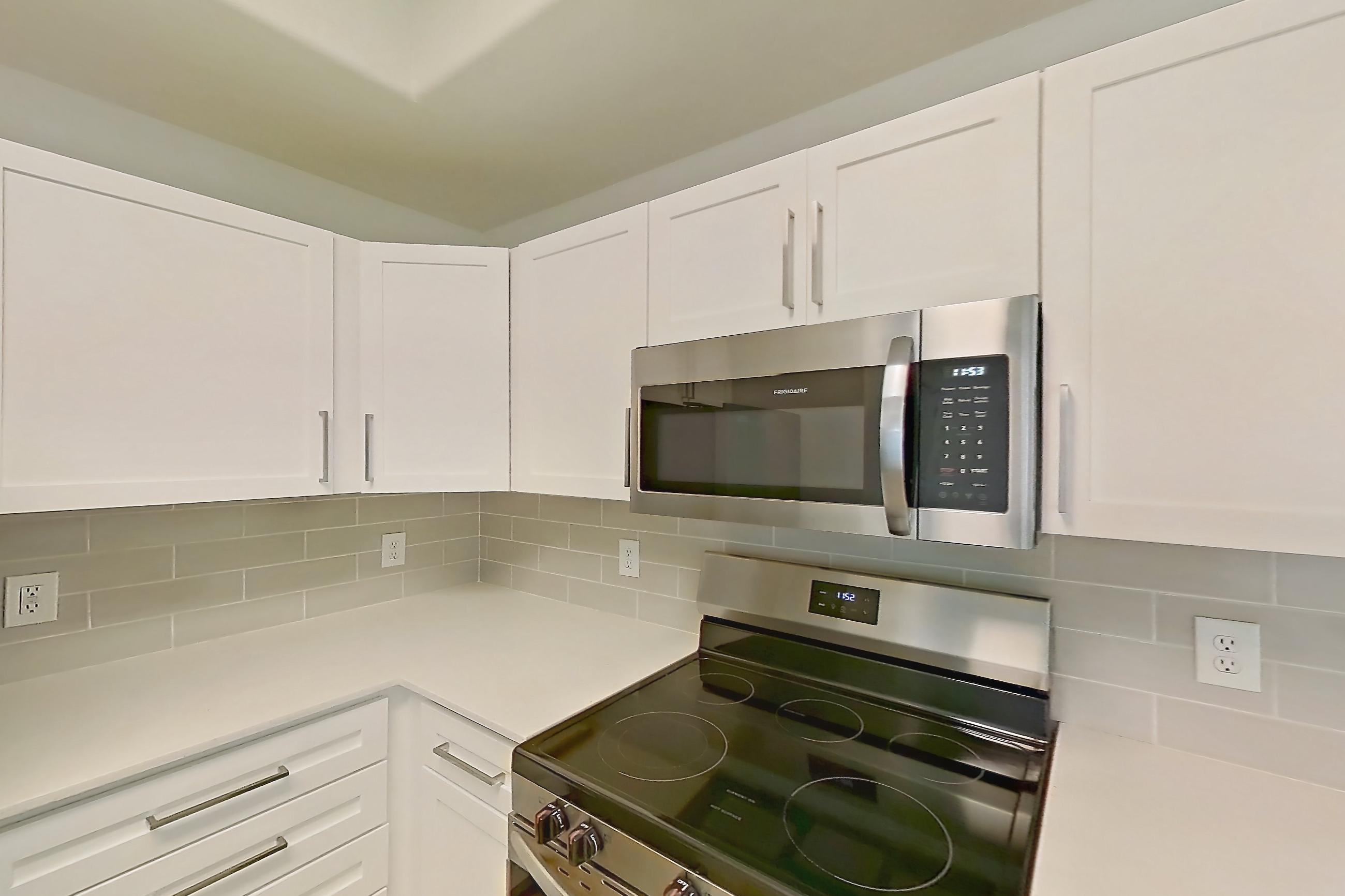 Kitchen with dishwasher, electric range, light stone countertops, light wood-finish flooring, microwave, oven/range, and stainless steel appliances, Apartment 2046 at Dobson 2222