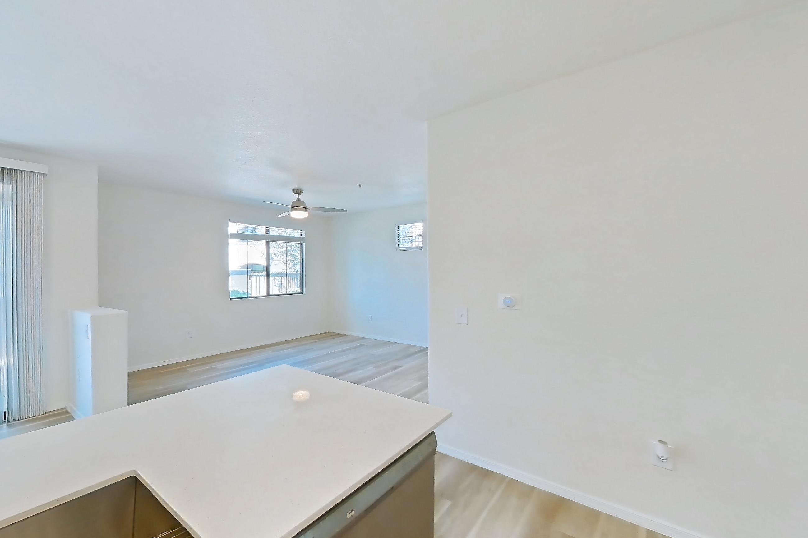 Kitchen with dishwasher, electric range, light countertops, light stone countertops, light wood-finish flooring, microwave, oven/range, and stainless steel appliances, Apartment 1033 at Dobson 2222