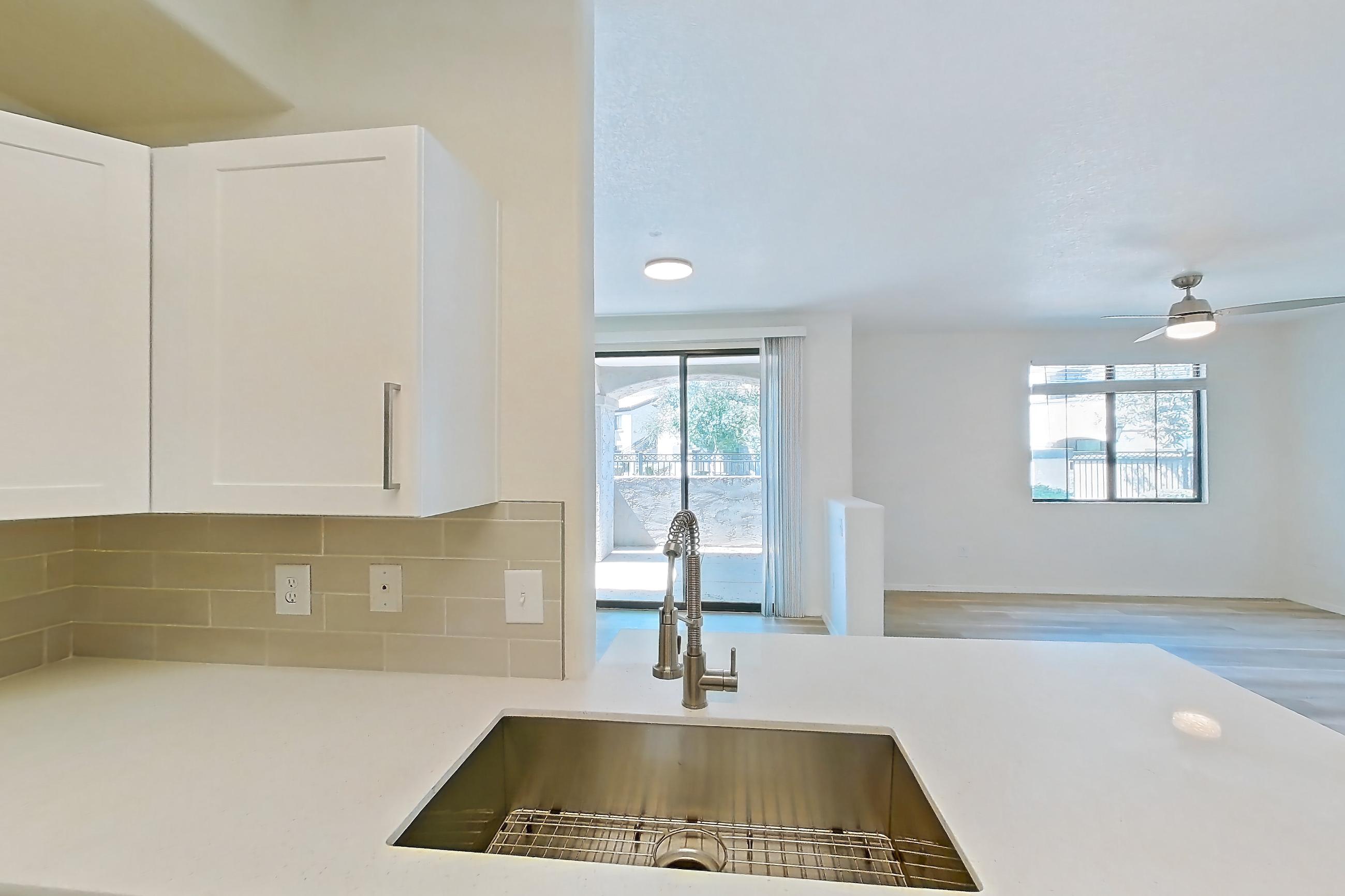 Kitchen with dishwasher, electric range, light countertops, light stone countertops, light wood-finish flooring, microwave, oven/range, and stainless steel appliances, Apartment 1033 at Dobson 2222