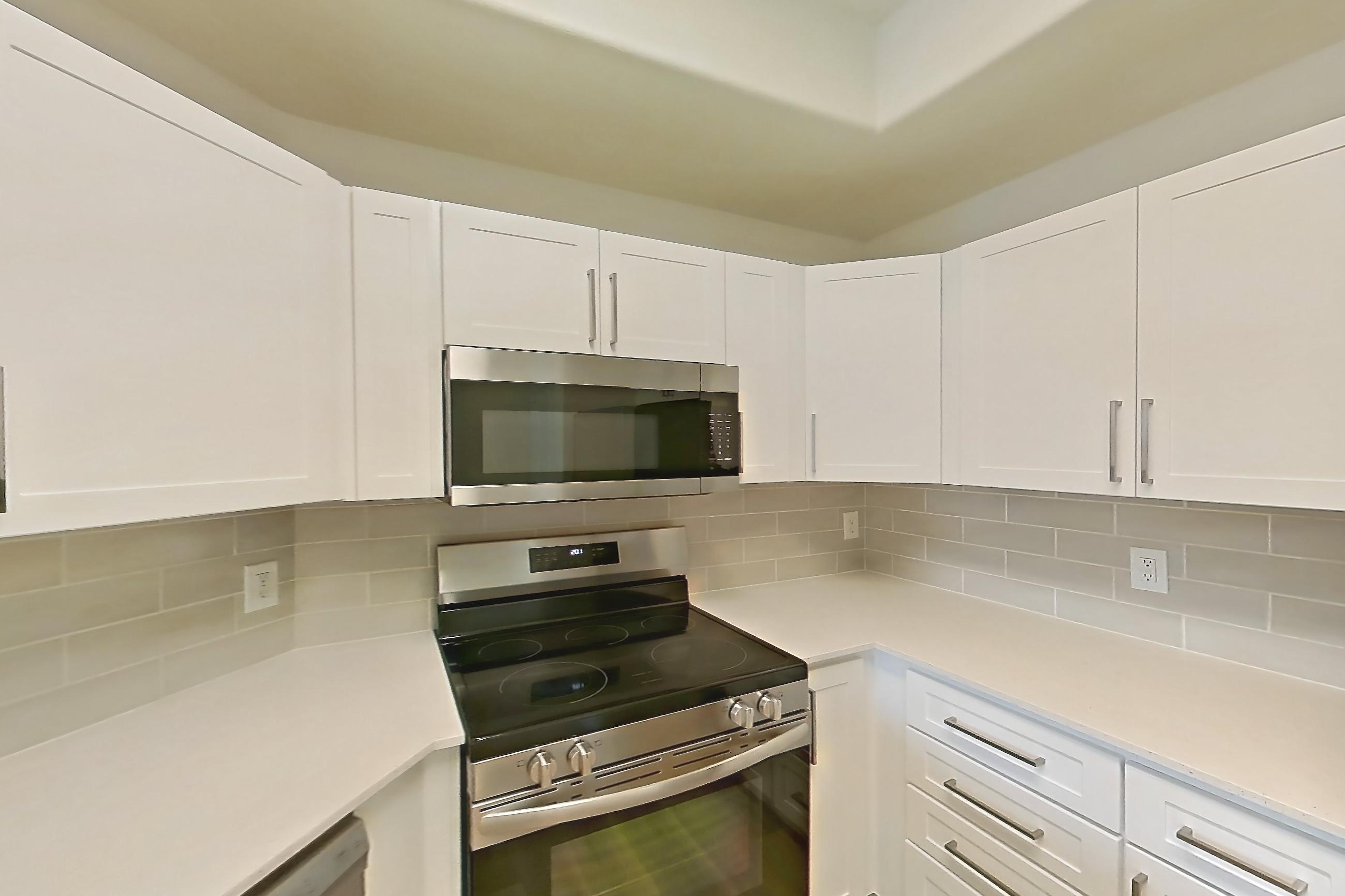 Kitchen with dishwasher, electric range, light stone countertops, light wood-finish flooring, microwave, oven/range, and stainless steel appliances, Apartment 1035 at Dobson 2222