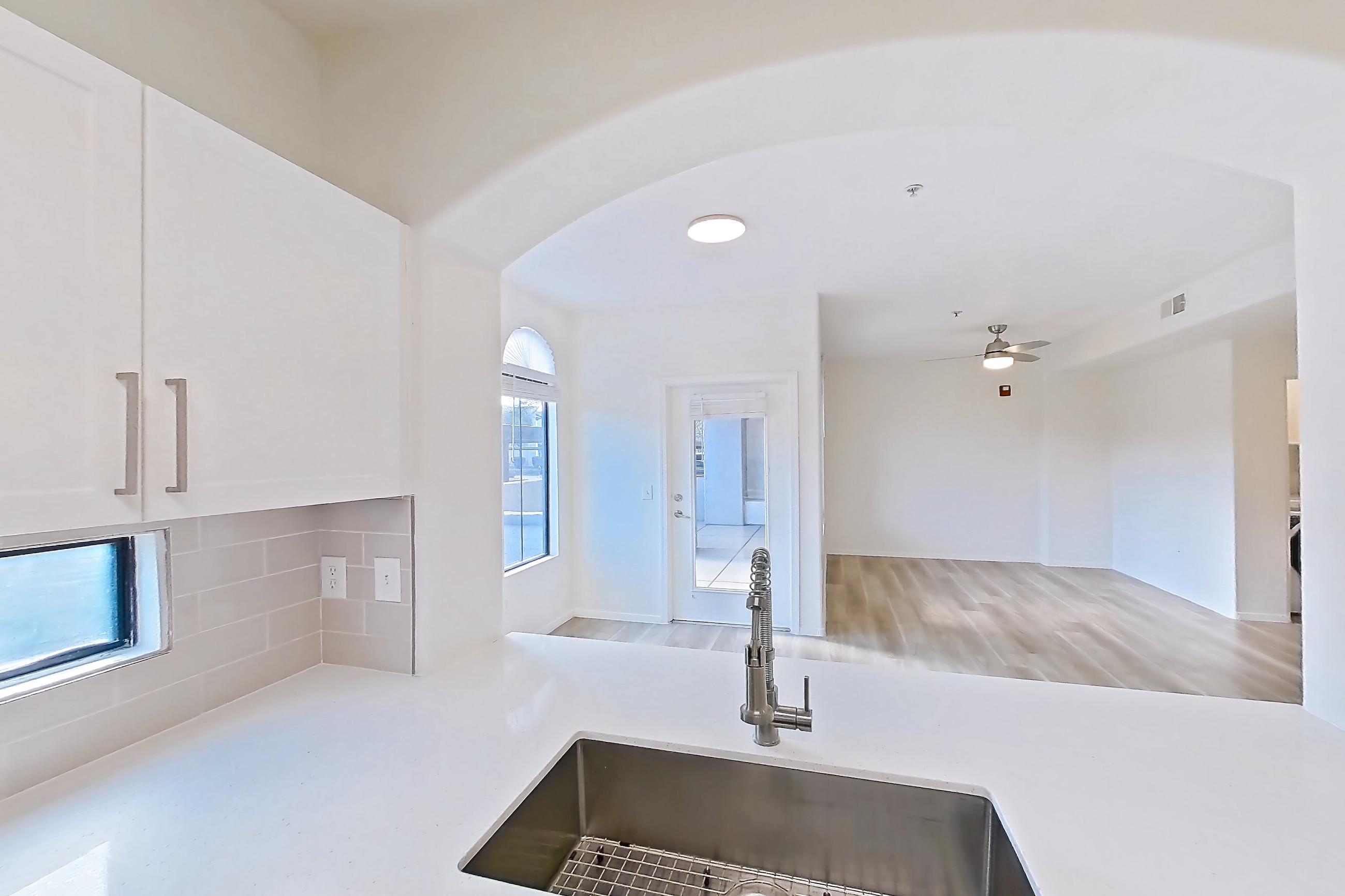 Kitchen with dishwasher, electric range, light countertops, light stone countertops, light wood-finish flooring, microwave, oven/range, and stainless steel appliances, Apartment 1087 at Dobson 2222