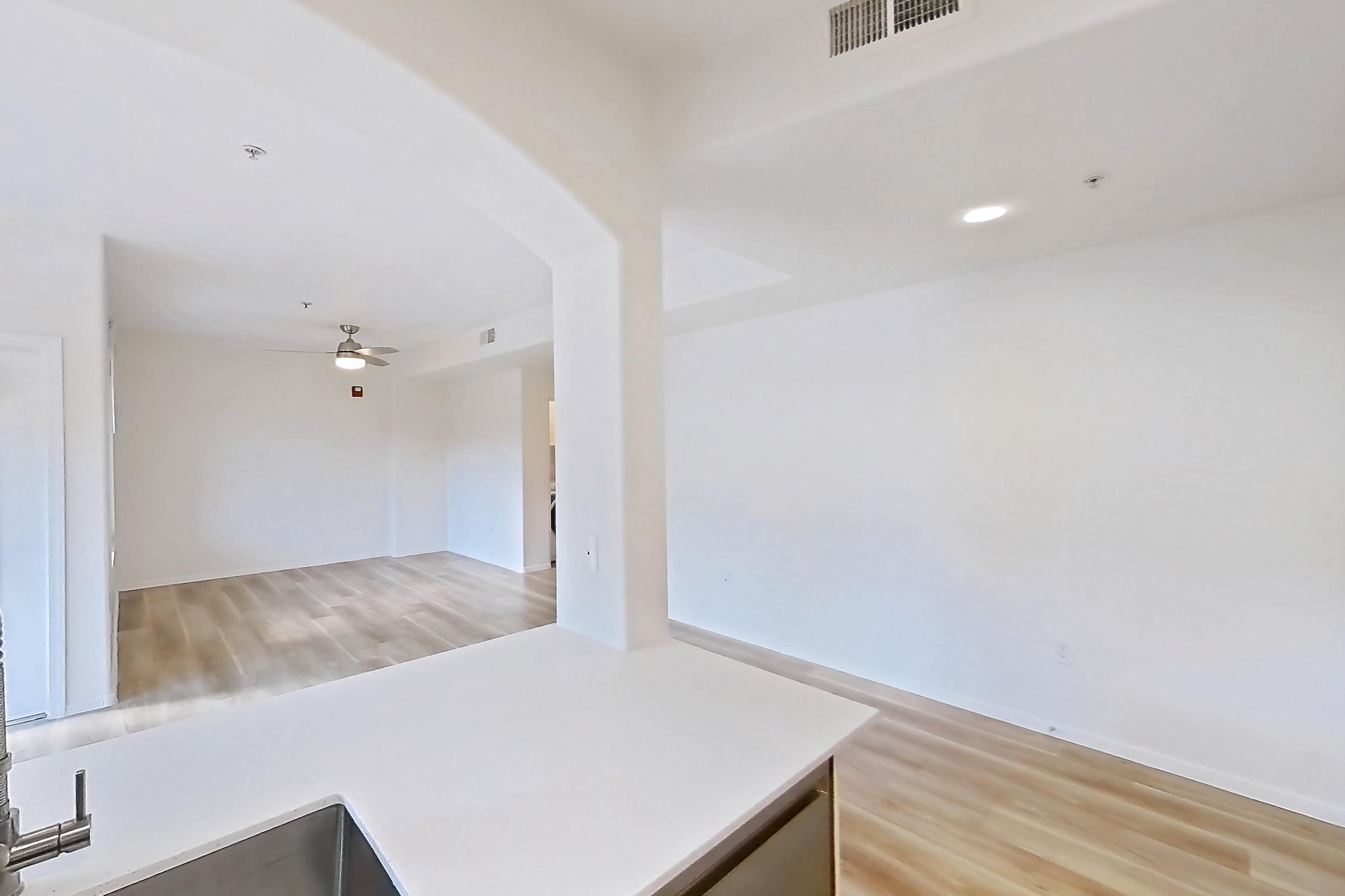 Kitchen with dishwasher, electric range, light countertops, light stone countertops, light wood-finish flooring, microwave, oven/range, and stainless steel appliances, Apartment 1087 at Dobson 2222