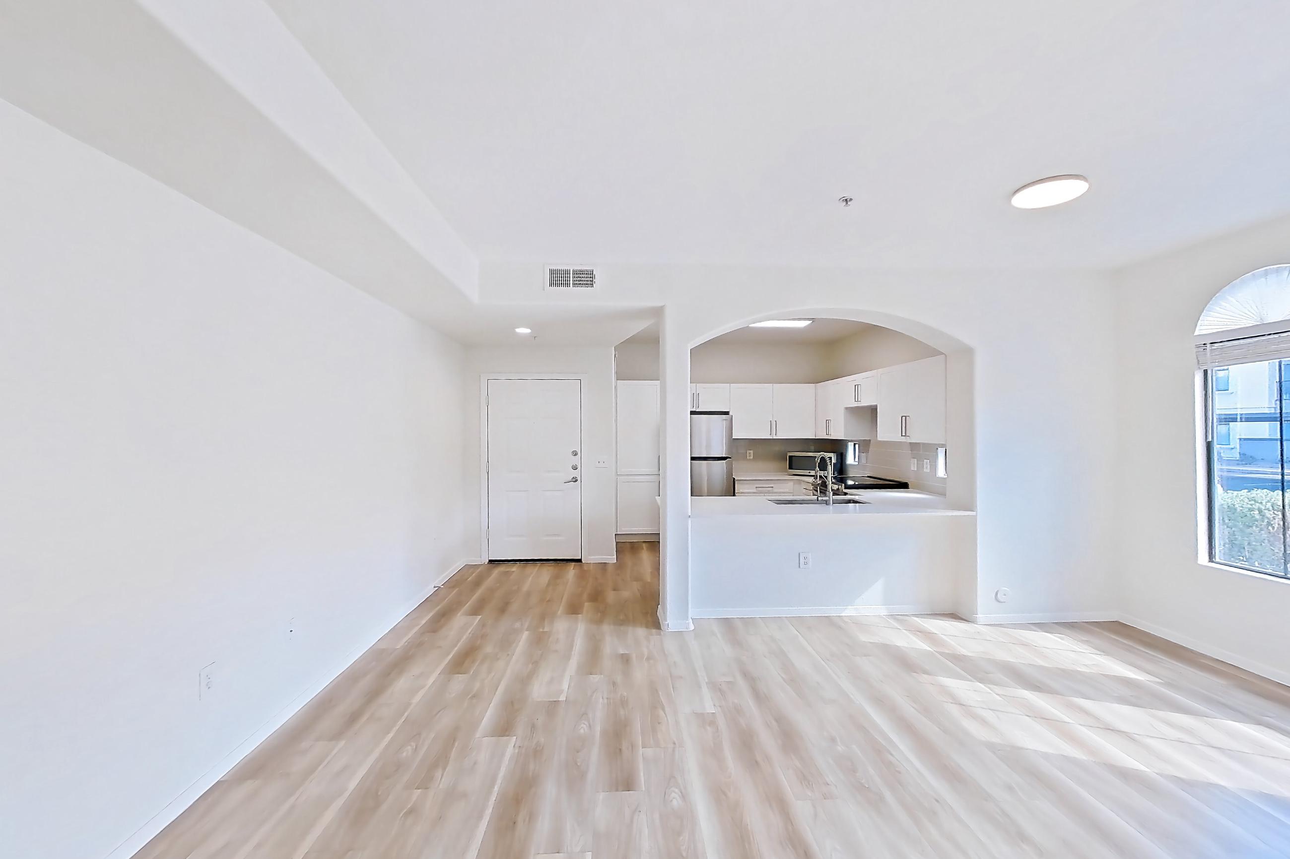 Living room with light wood-finish flooring, microwave, refrigerator, and stainless steel appliances, Apartment 1087 at Dobson 2222