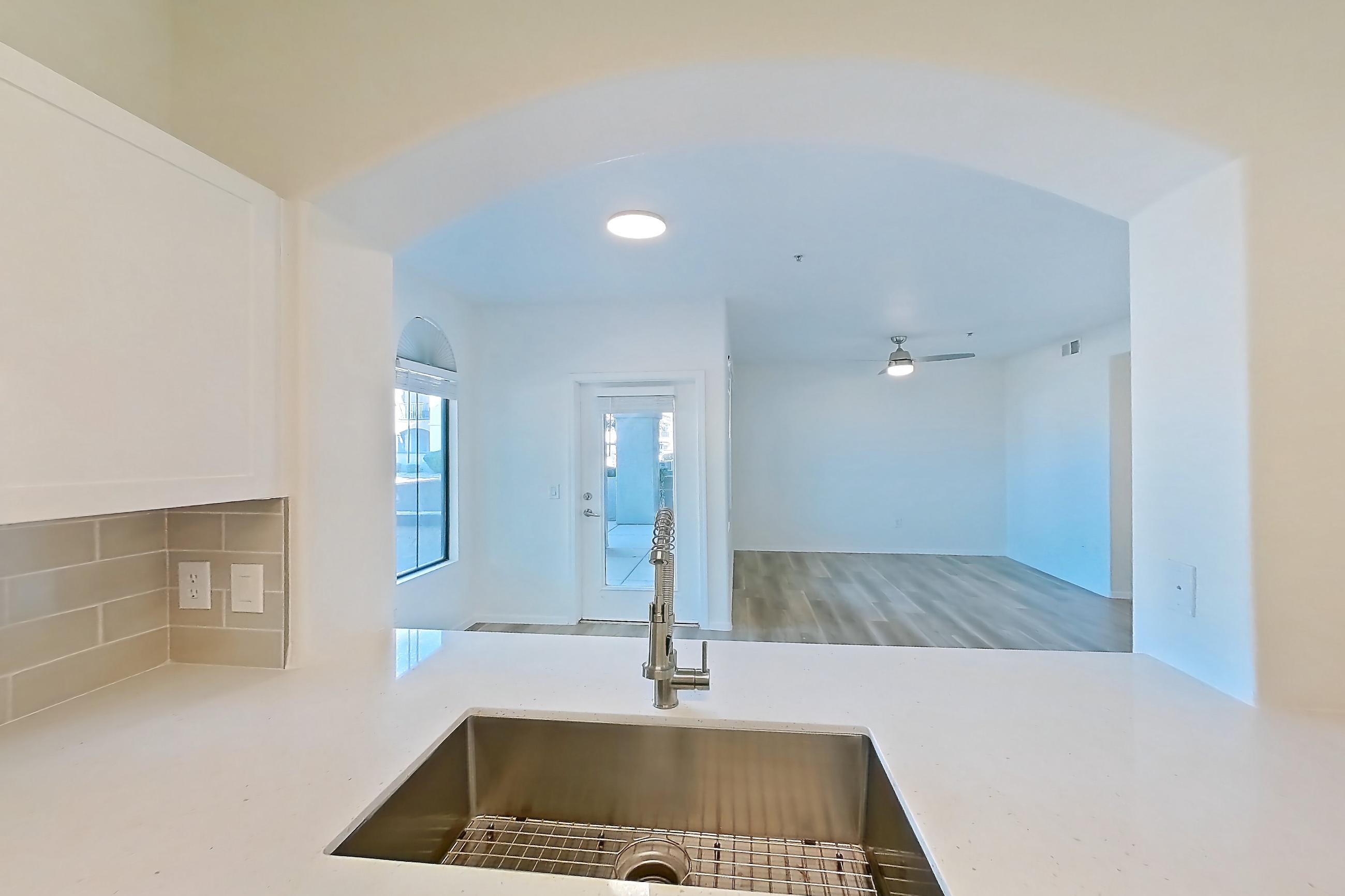 Kitchen with dishwasher, electric range, light countertops, light stone countertops, light wood-finish flooring, microwave, oven/range, and stainless steel appliances, Apartment 1091 at Dobson 2222