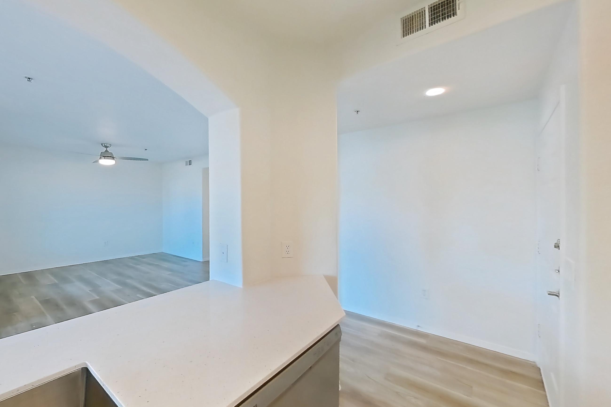 Kitchen with dishwasher, electric range, light countertops, light stone countertops, light wood-finish flooring, microwave, oven/range, and stainless steel appliances, Apartment 1091 at Dobson 2222