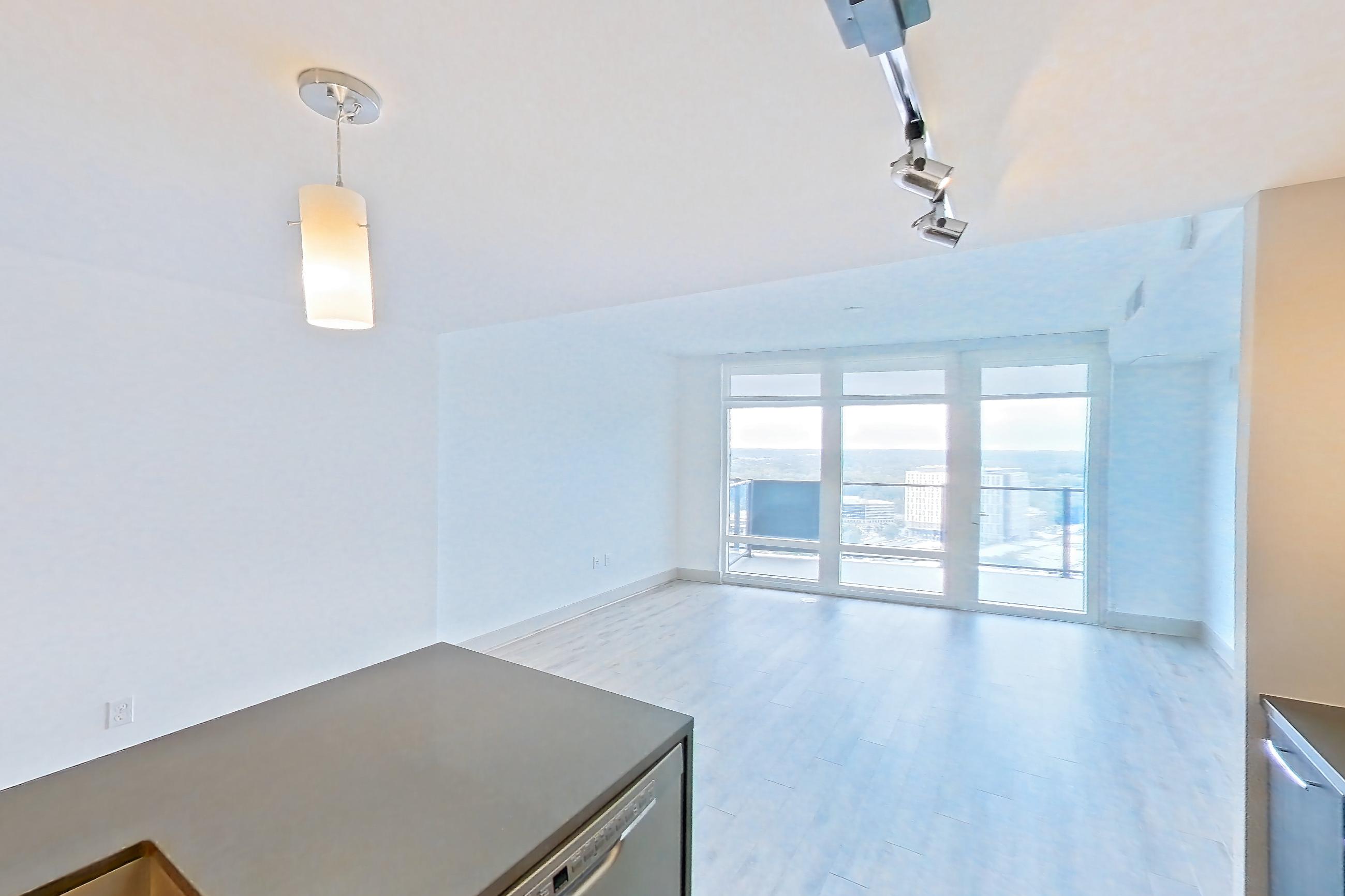Kitchen with dark countertops, dark stone countertops, dishwasher, electric range, kitchen island, light wood-finish flooring, oven/range, and stainless steel appliances, Apartment 3013 at Adaire