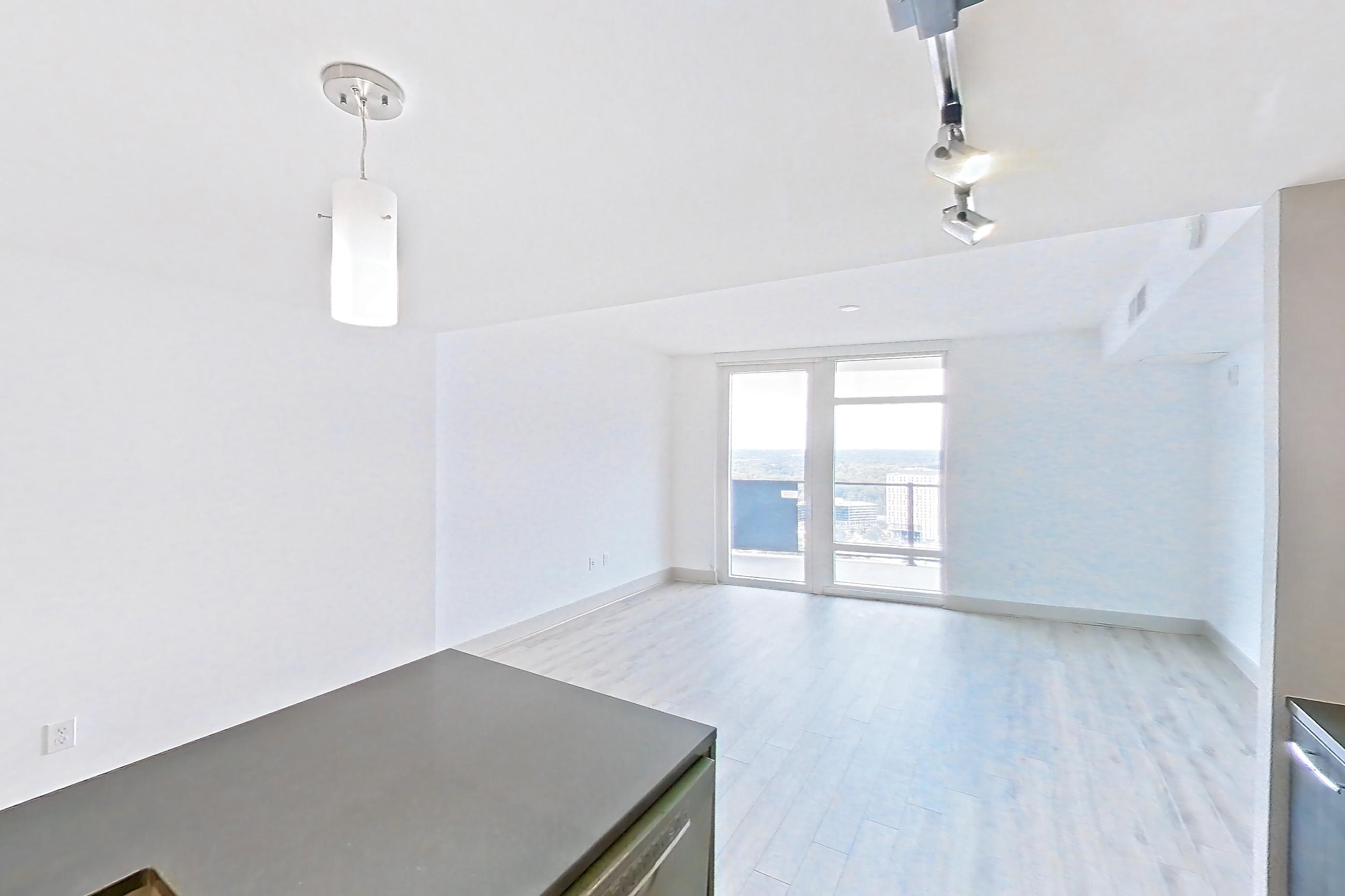 Kitchen with dark countertops, dark stone countertops, dishwasher, electric range, kitchen island, light wood-finish flooring, oven/range, refrigerator, and stainless steel appliances, Apartment 3113 at Adaire