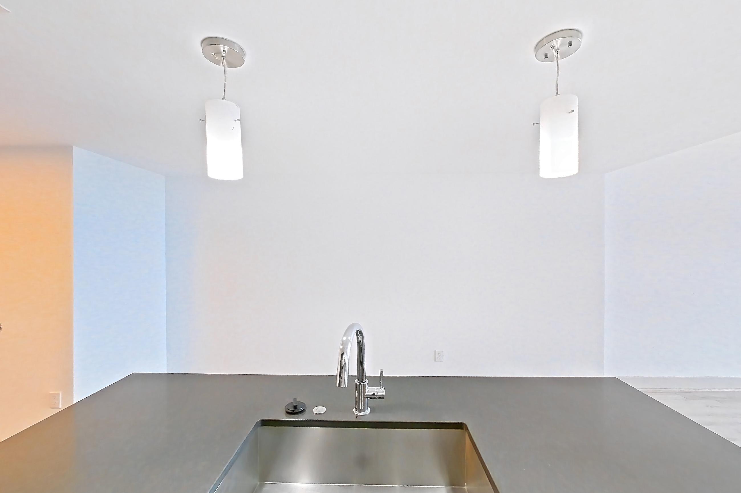 Kitchen with dark countertops, dark stone countertops, dishwasher, electric range, kitchen island, light wood-finish flooring, oven/range, refrigerator, and stainless steel appliances, Apartment 3113 at Adaire