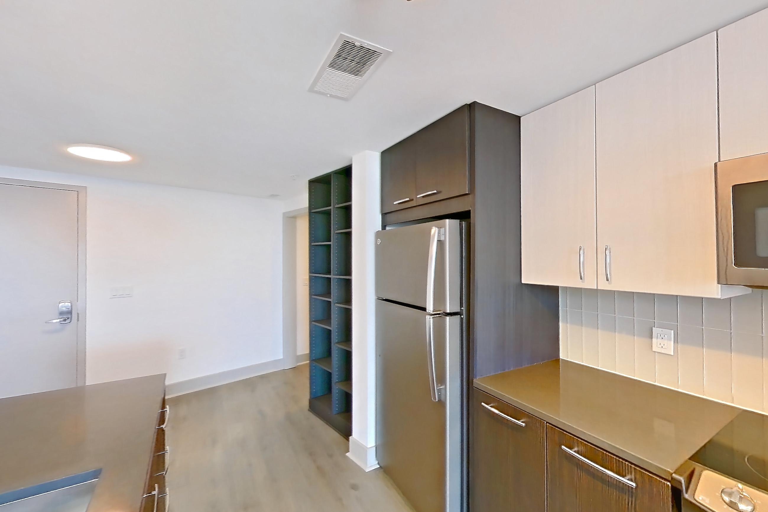 Kitchen with dark countertops, electric range, light wood-finish flooring, oven/range, refrigerator, and stainless steel appliances, Apartment 1314 at Adaire