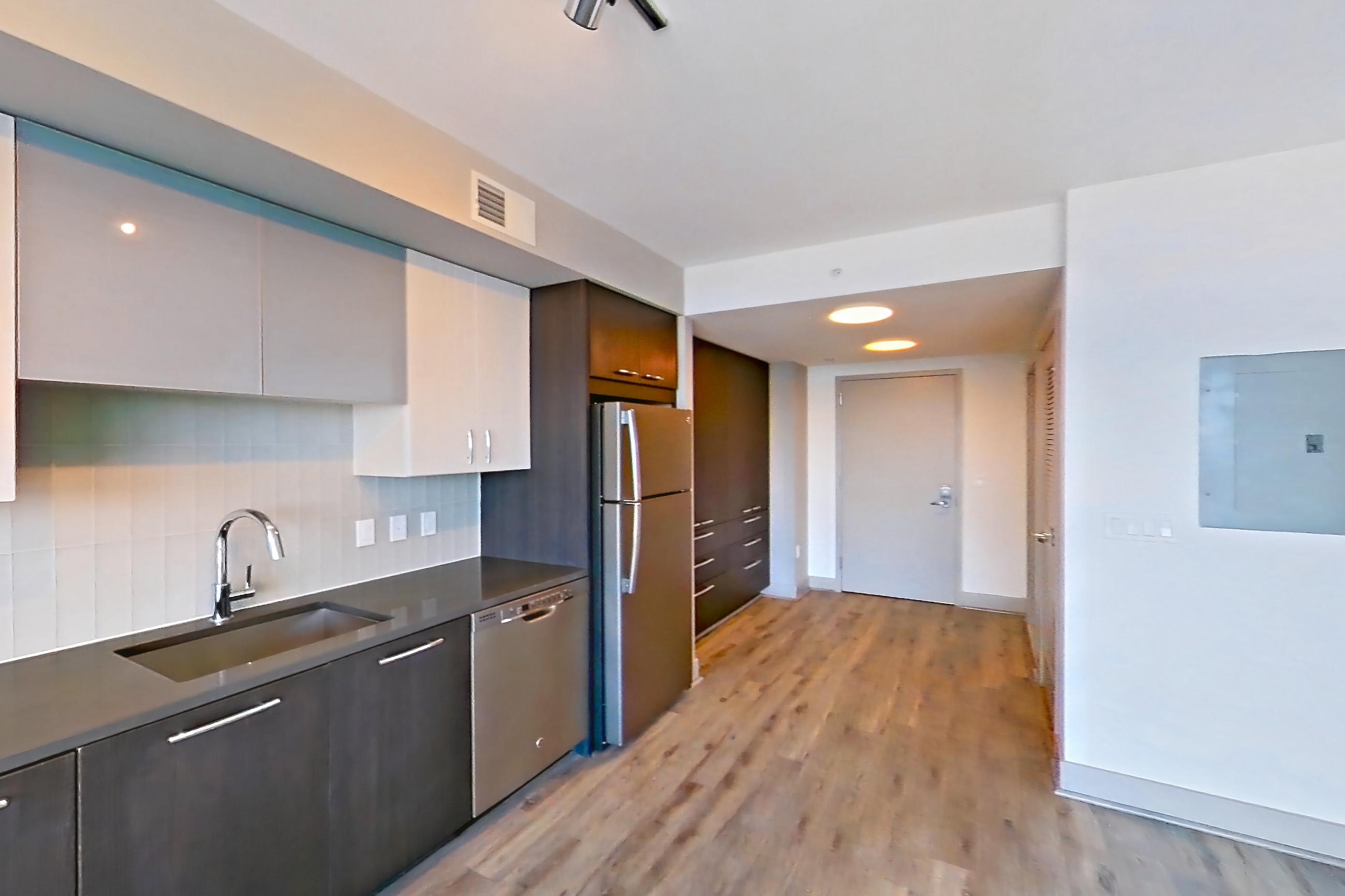Kitchen with dark countertops, dishwasher, electric range, light wood-finish flooring, microwave, oven/range, refrigerator, and stainless steel appliances, Apartment 3215 at Adaire