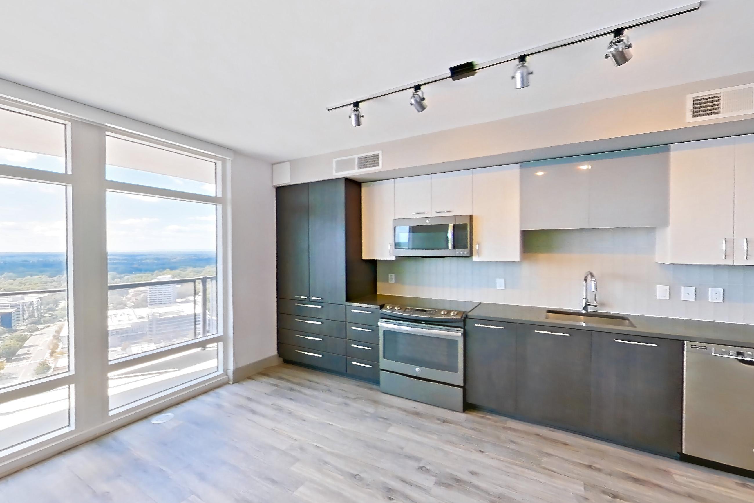 Living room with dark countertops, dishwasher, electric range, light countertops, light wood-finish flooring, microwave, oven/range, refrigerator, and stainless steel appliances, Apartment 3215 at Adaire