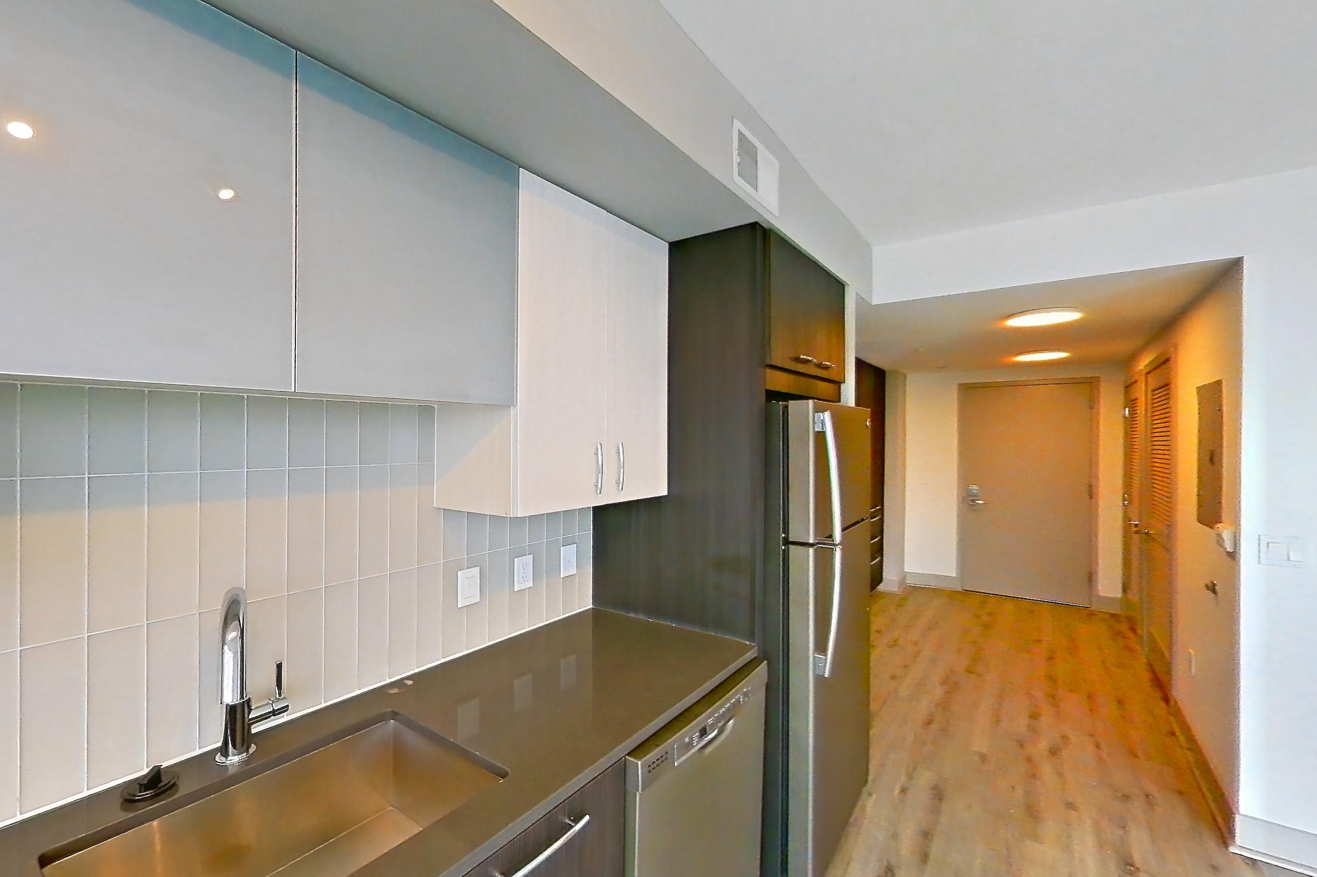 Kitchen with dark countertops, dishwasher, electric range, light wood-finish flooring, microwave, oven/range, refrigerator, and stainless steel appliances, Apartment 1702 at Adaire