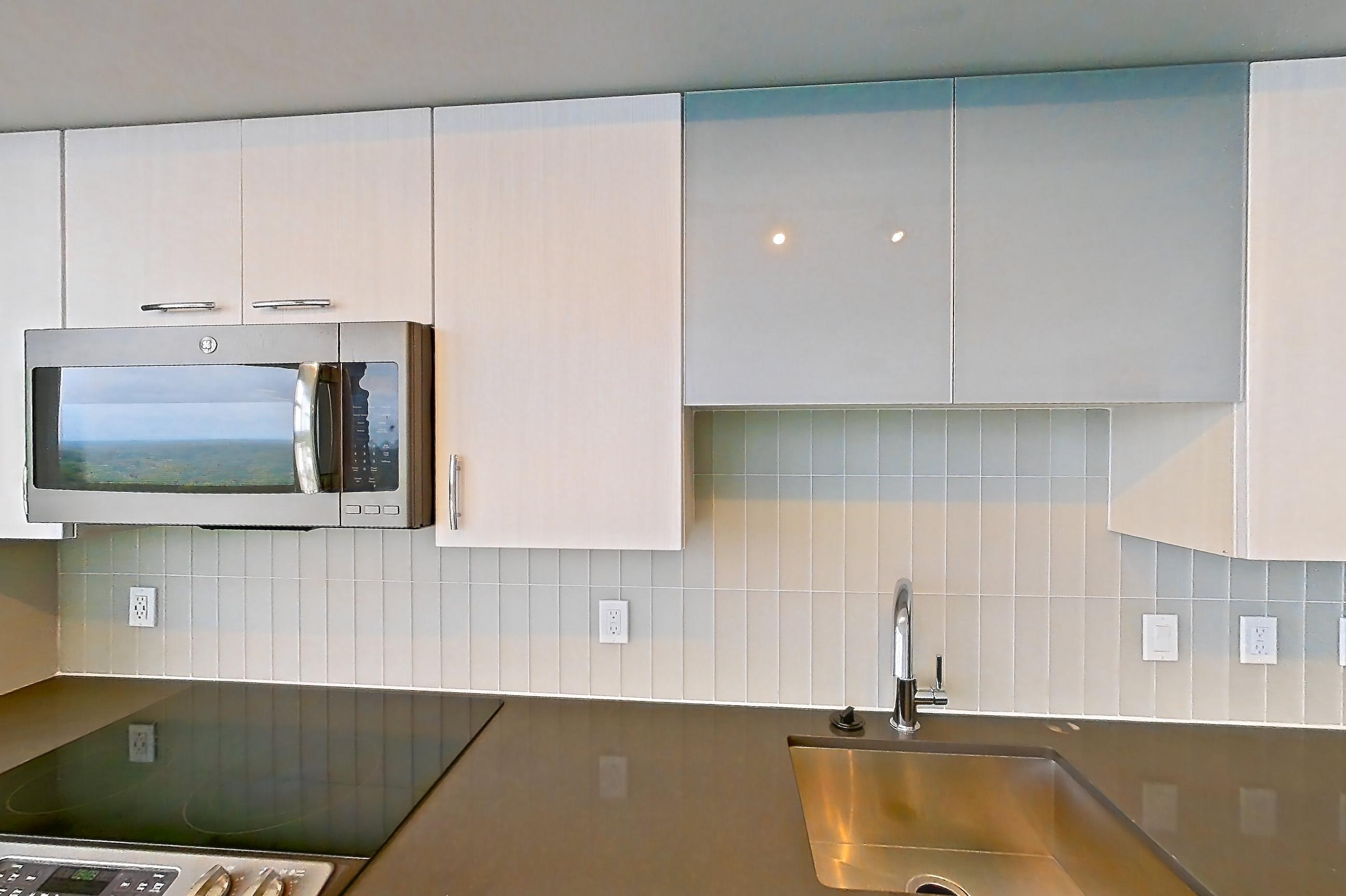 Kitchen with dark countertops, dishwasher, electric range, light wood-finish flooring, microwave, oven/range, refrigerator, and stainless steel appliances, Apartment 1702 at Adaire