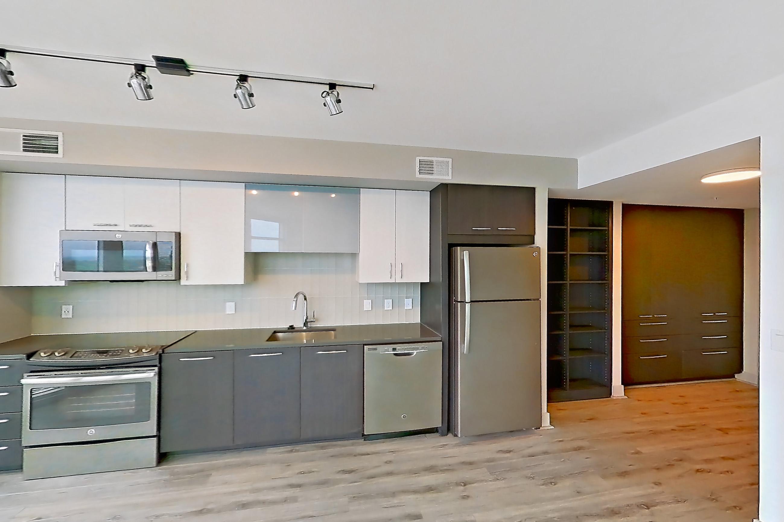 Living space with dark countertops, dishwasher, electric range, light wood-finish flooring, oven/range, refrigerator, and stainless steel appliances, Apartment 1702 at Adaire