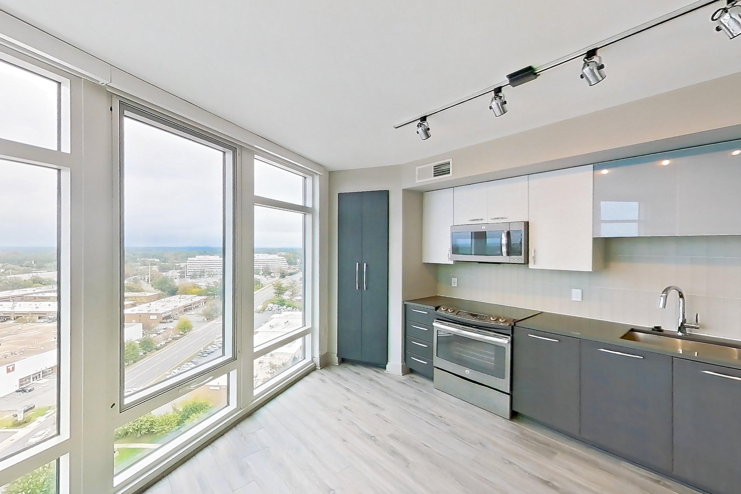 Living space with dark countertops, dishwasher, electric range, light wood-finish flooring, oven/range, refrigerator, and stainless steel appliances, Apartment 1702 at Adaire