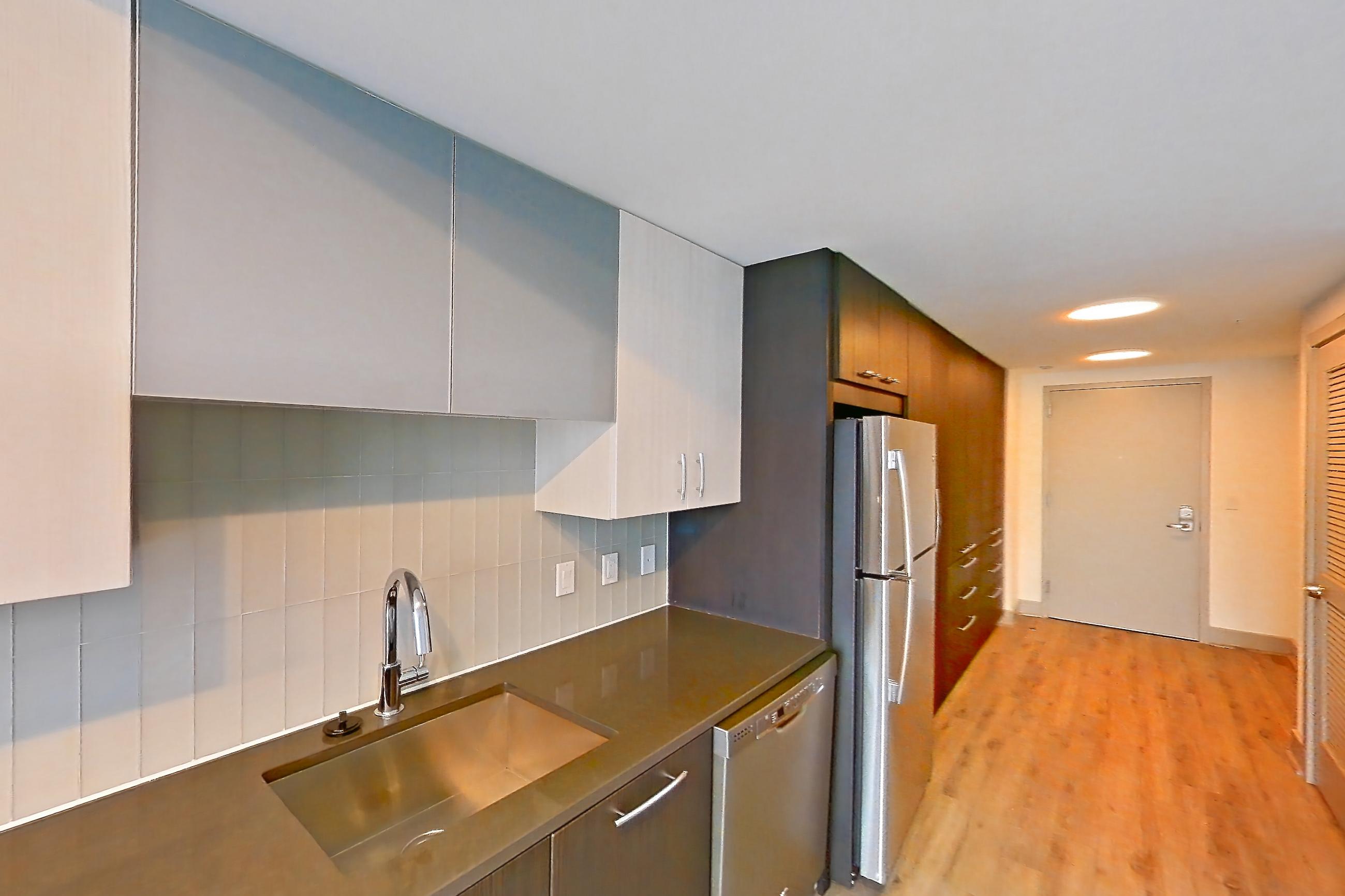 Kitchen with dark countertops, dishwasher, electric range, light countertops, light wood-finish flooring, microwave, oven/range, refrigerator, and stainless steel appliances, Apartment 1803 at Adaire