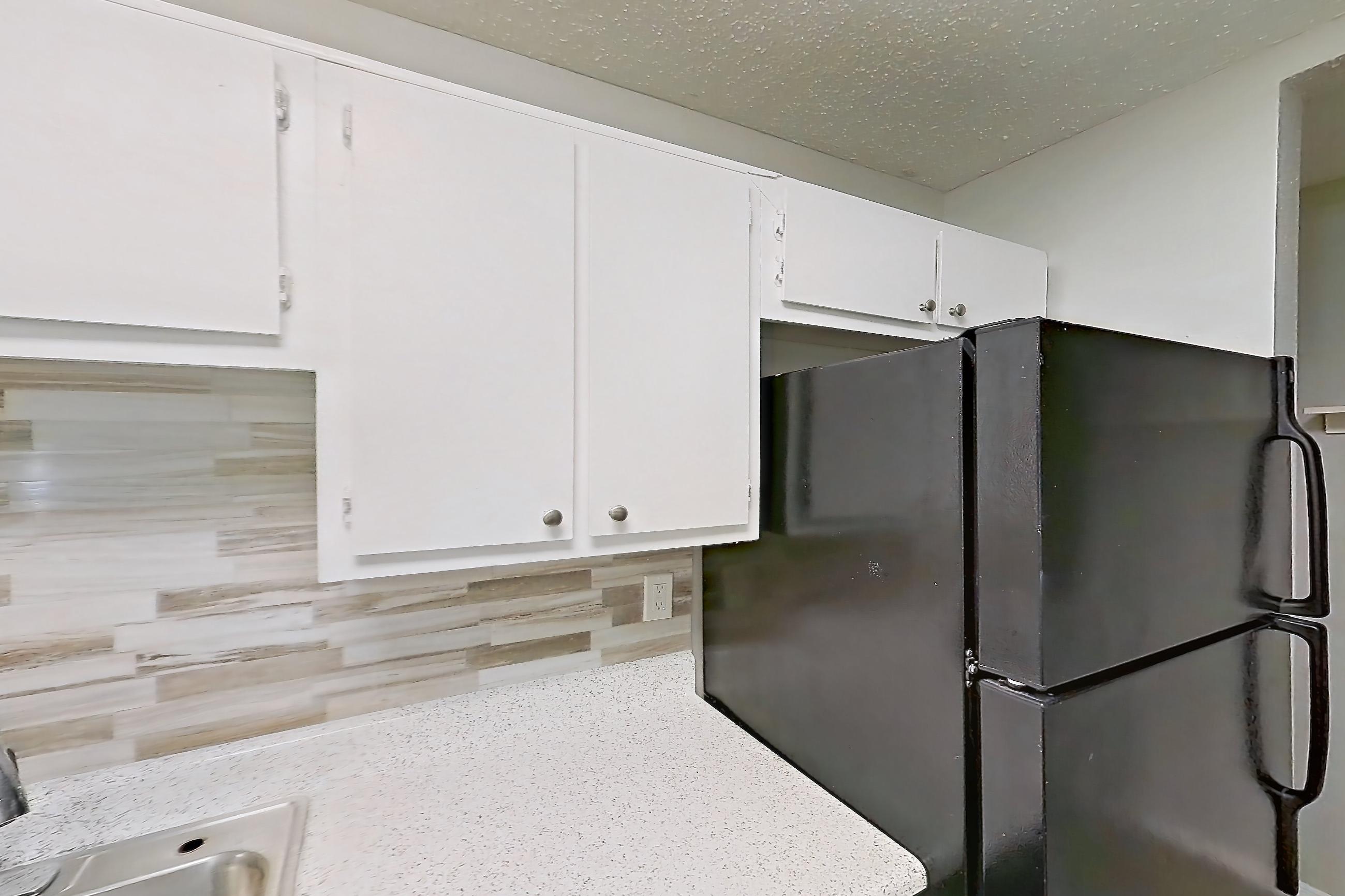 Kitchen with black appliances, dishwasher, electric range, light countertops, light stone countertops, light wood-finish flooring, oven/range, and range hood, Apartment 322 at Arbor Creek
