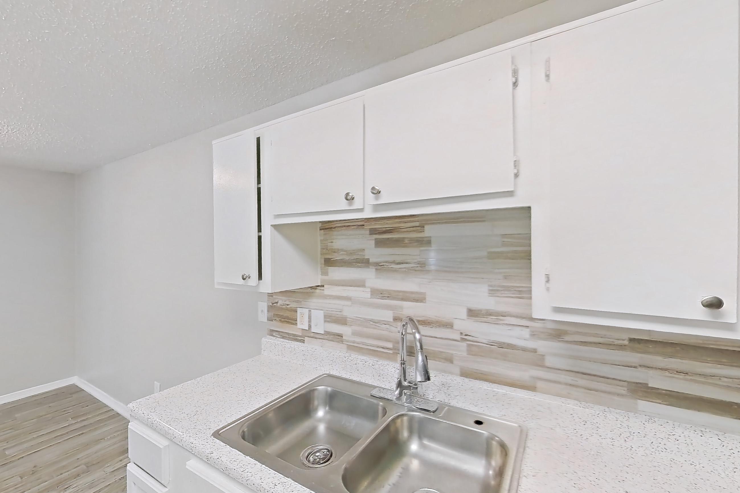 Kitchen with black appliances, dishwasher, electric range, light countertops, light stone countertops, light wood-finish flooring, oven/range, and range hood, Apartment 322 at Arbor Creek