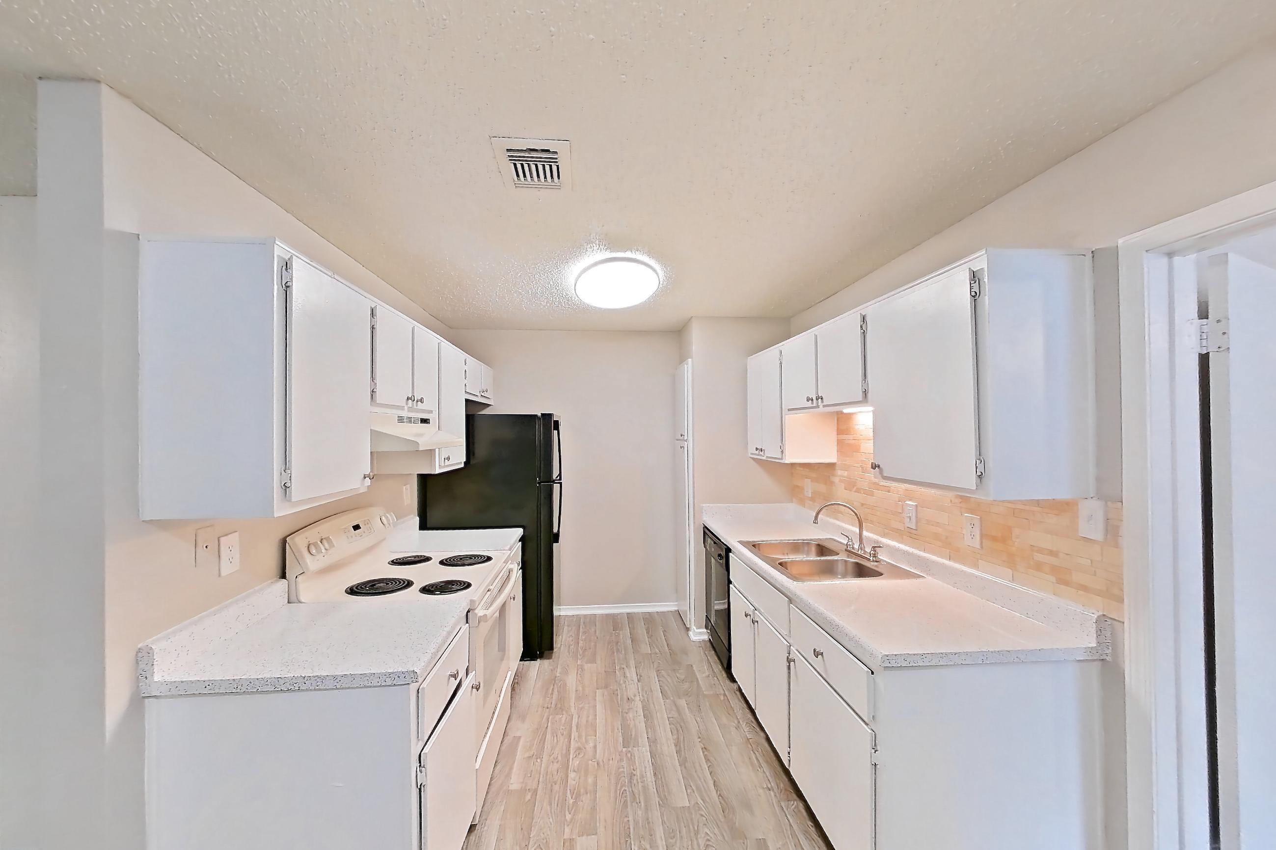 Dining room with black appliances, dishwasher, electric range, fireplace, light countertops, light wood-finish flooring, oven/range, refrigerator, and white appliances, Apartment 1011 at Arbor Creek