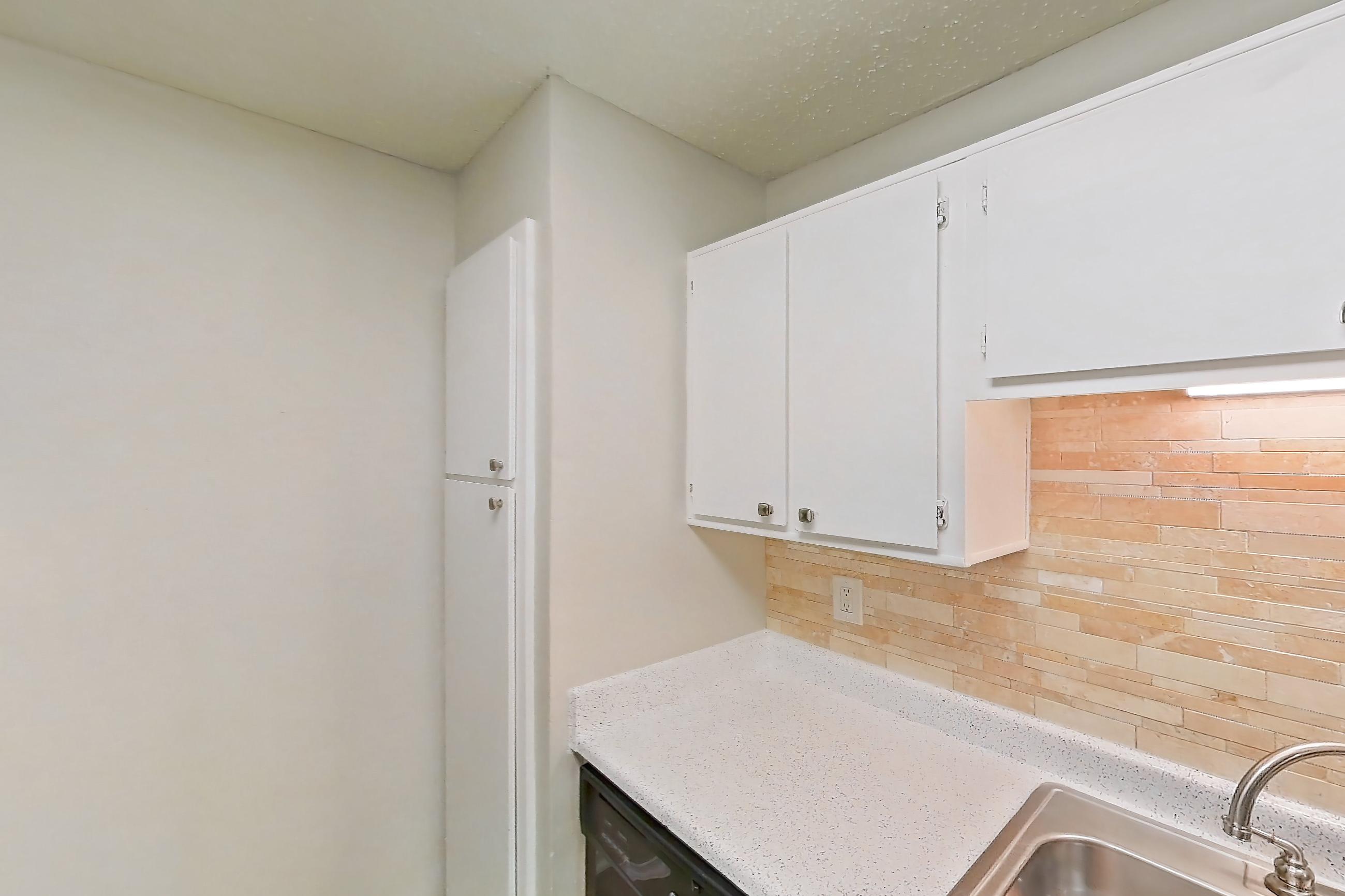 Kitchen with black appliances, dishwasher, electric range, light countertops, light stone countertops, light wood-finish flooring, oven/range, refrigerator, and white appliances, Apartment 1011 at Arbor Creek