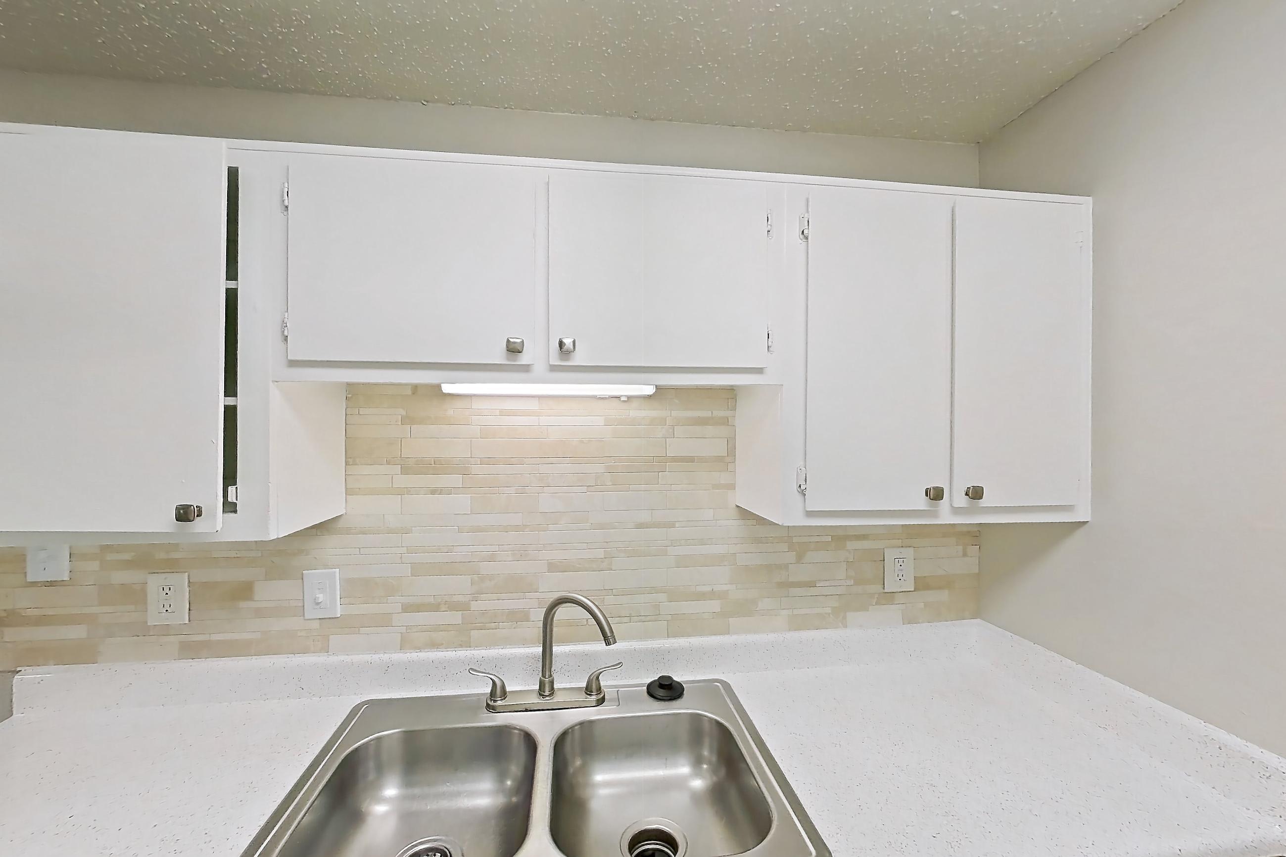 Kitchen with dishwasher, electric range, light countertops, light stone countertops, light wood-finish flooring, oven/range, refrigerator, and white appliances, Apartment 122 at Arbor Creek