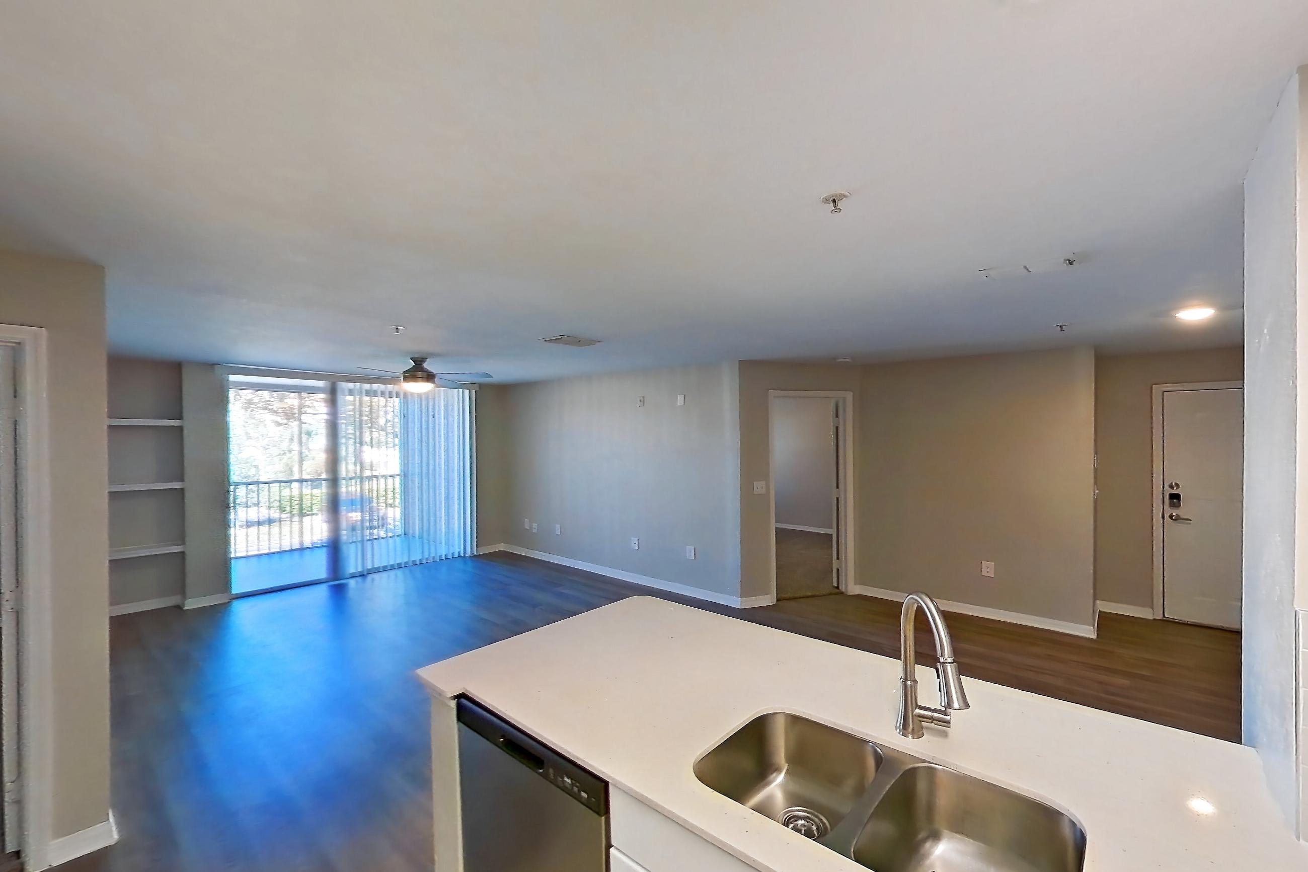 Kitchen with black appliances, dishwasher, electric range, light countertops, light stone countertops, light tile flooring, microwave, oven/range, refrigerator, and stainless steel appliances, Apartment 02-207 at Boot Ranch
