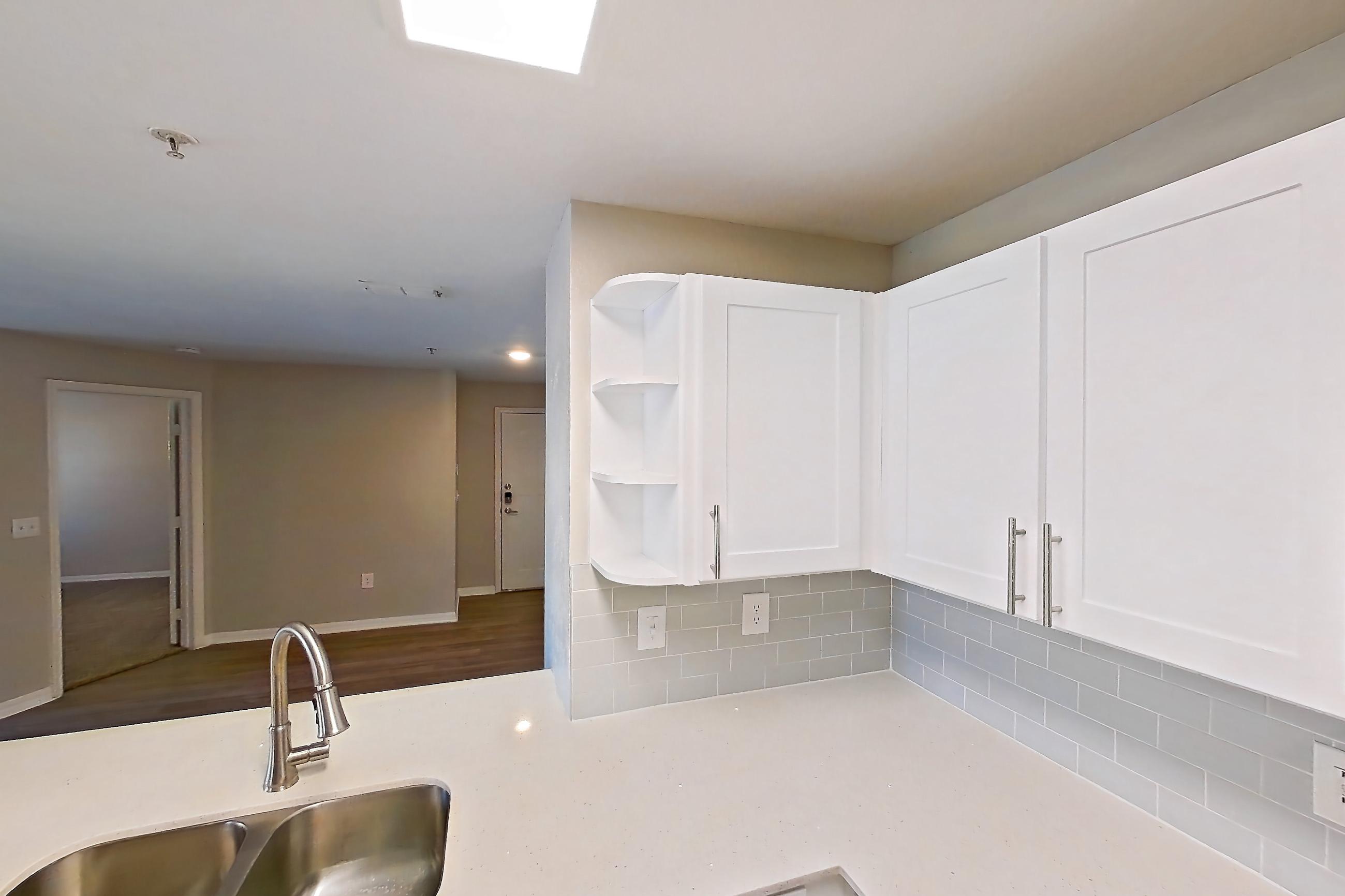 Kitchen with black appliances, dishwasher, electric range, light countertops, light stone countertops, light tile flooring, microwave, oven/range, refrigerator, and stainless steel appliances, Apartment 02-207 at Boot Ranch