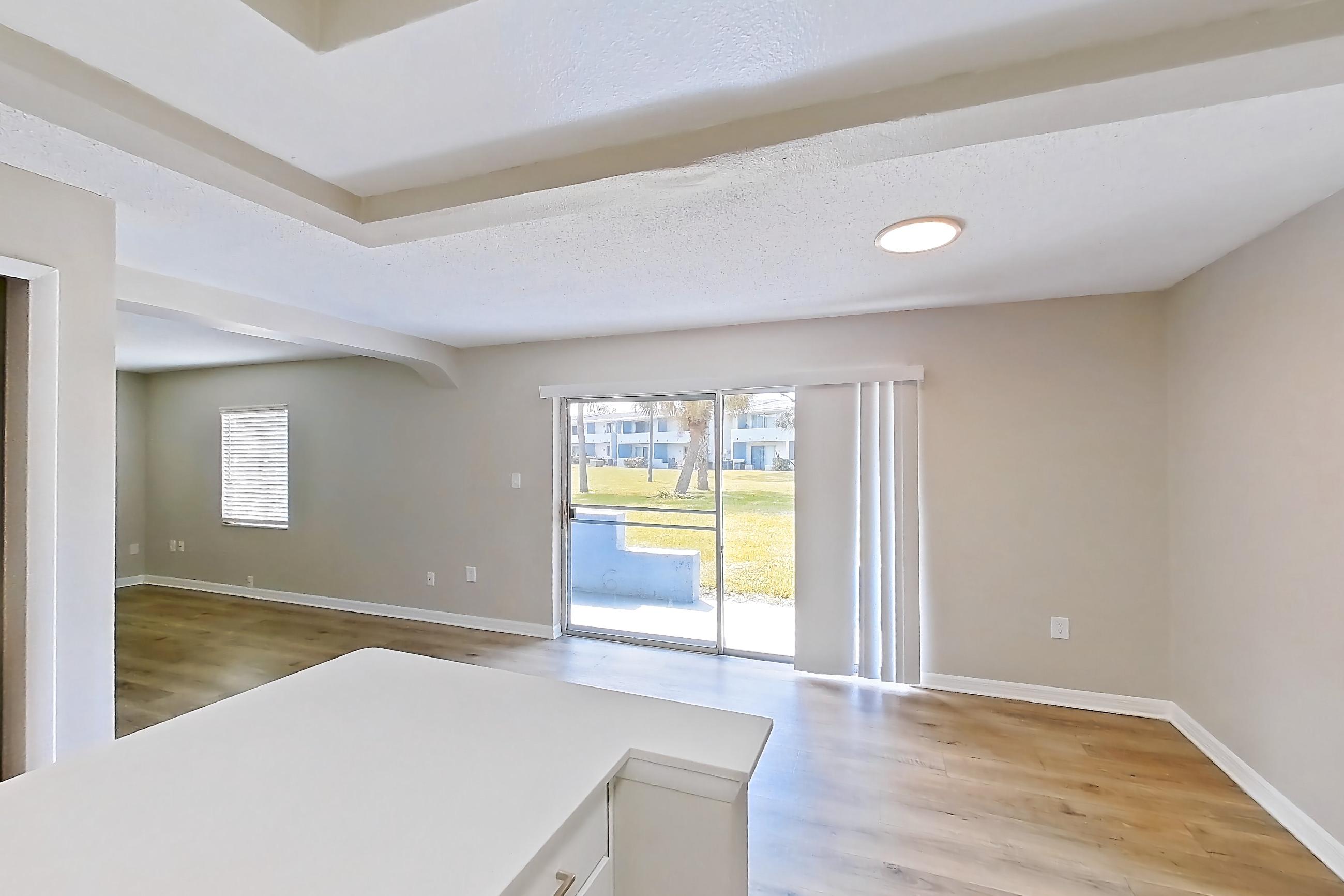 Kitchen with black appliances, electric range, in-unit laundry, light countertops, light wood-finish flooring, oven/range, range hood, refrigerator, and stainless steel appliances, Apartment 113 at Venue at Winter Park