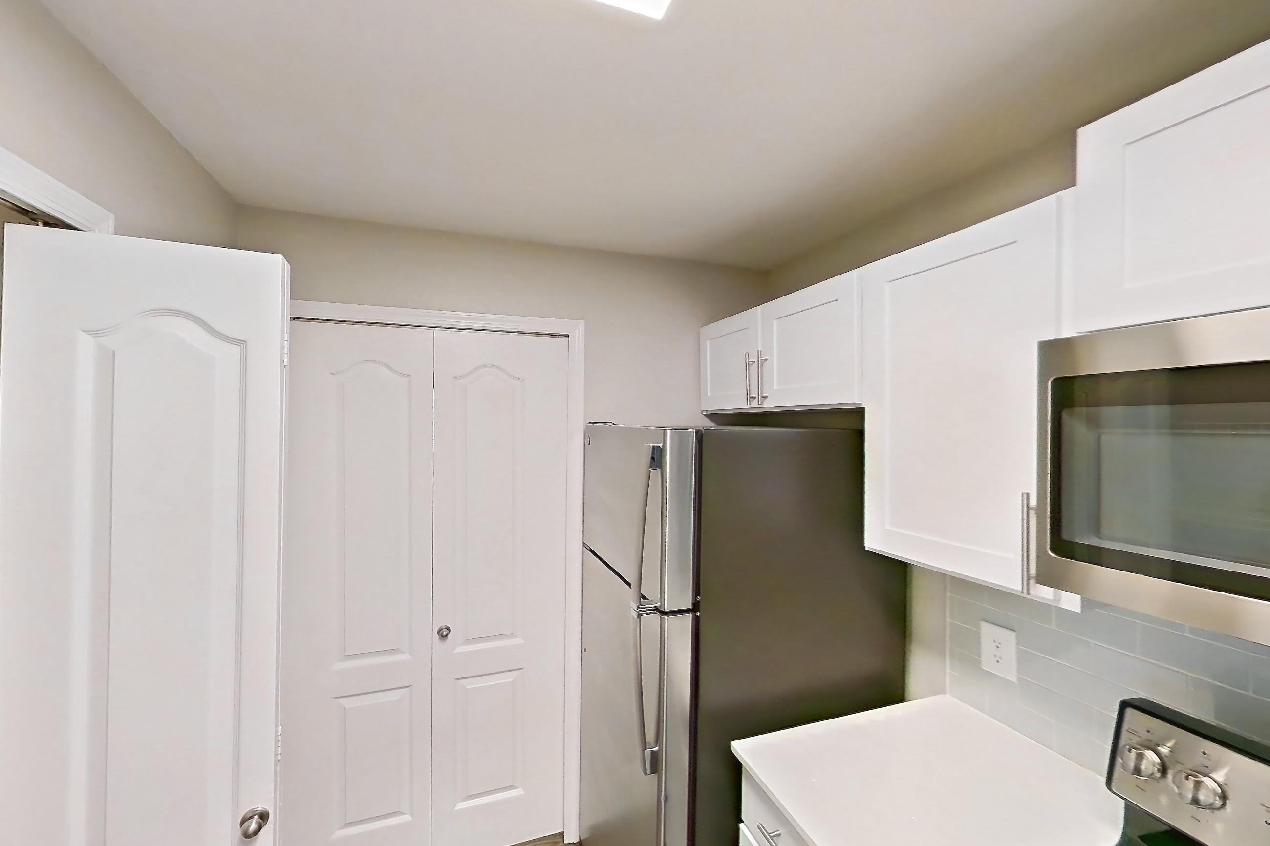 Kitchen with dark wood-finish flooring, dishwasher, electric range, light countertops, light stone countertops, light wood-finish flooring, microwave, oven/range, refrigerator, and stainless steel appliances, Apartment 02-301 at Boot Ranch
