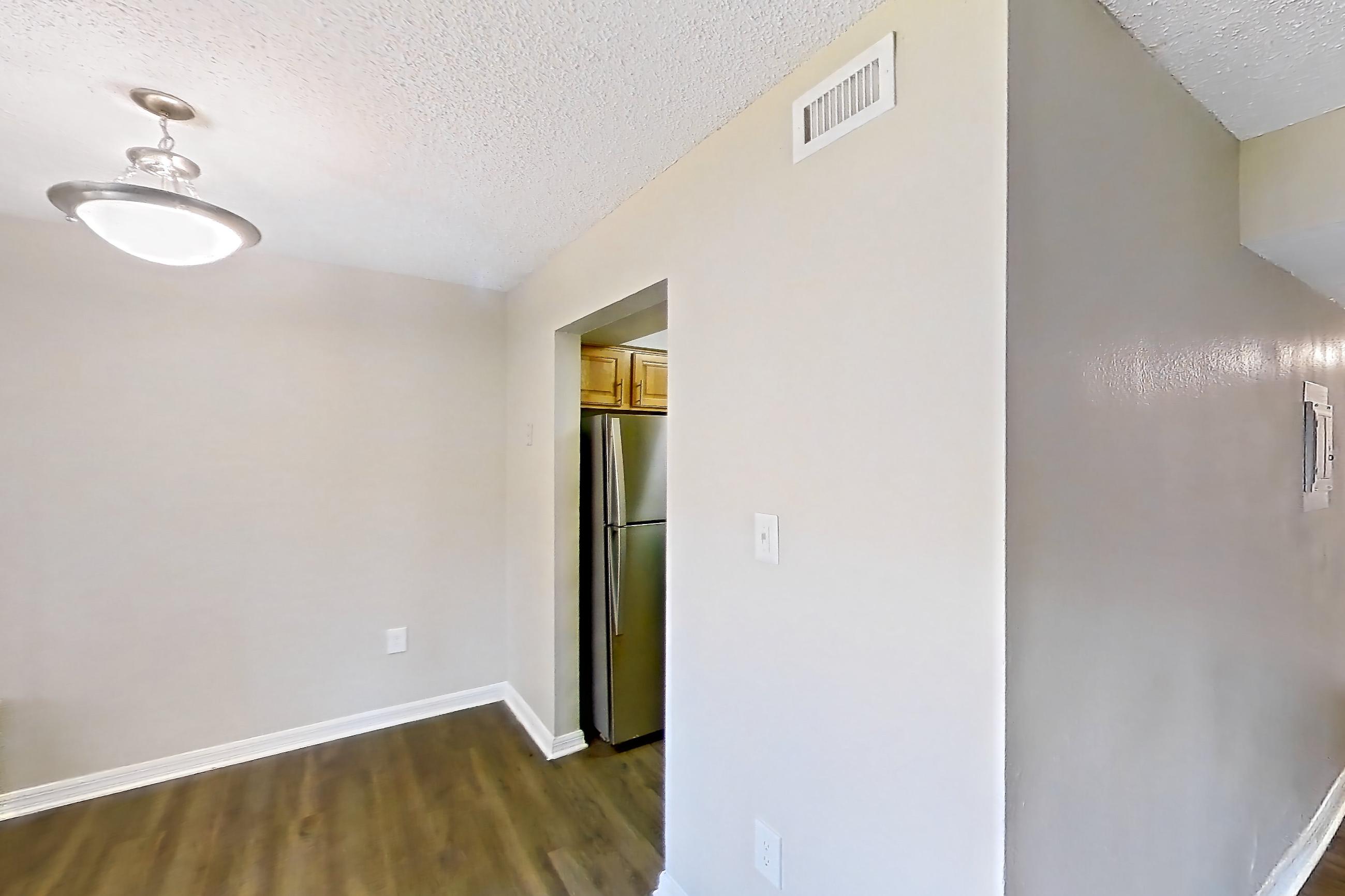 Living space with dark wood-finish flooring, refrigerator, and stainless steel appliances, Apartment 121 at Venue at Winter Park
