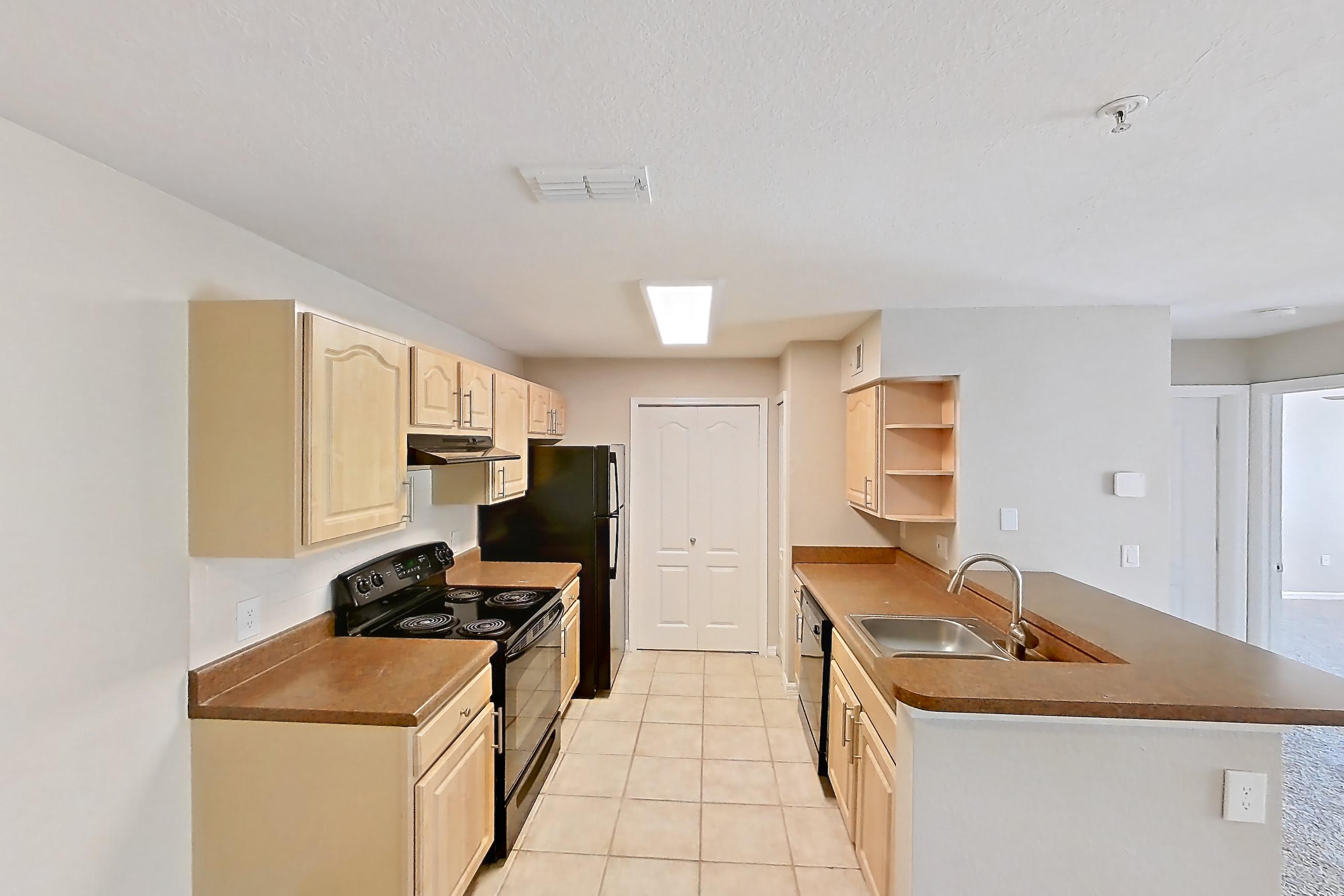 Dining room with black appliances, dark countertops, dishwasher, electric range, light carpet, light tile flooring, oven/range, and refrigerator, Apartment 04-106 at Boot Ranch
