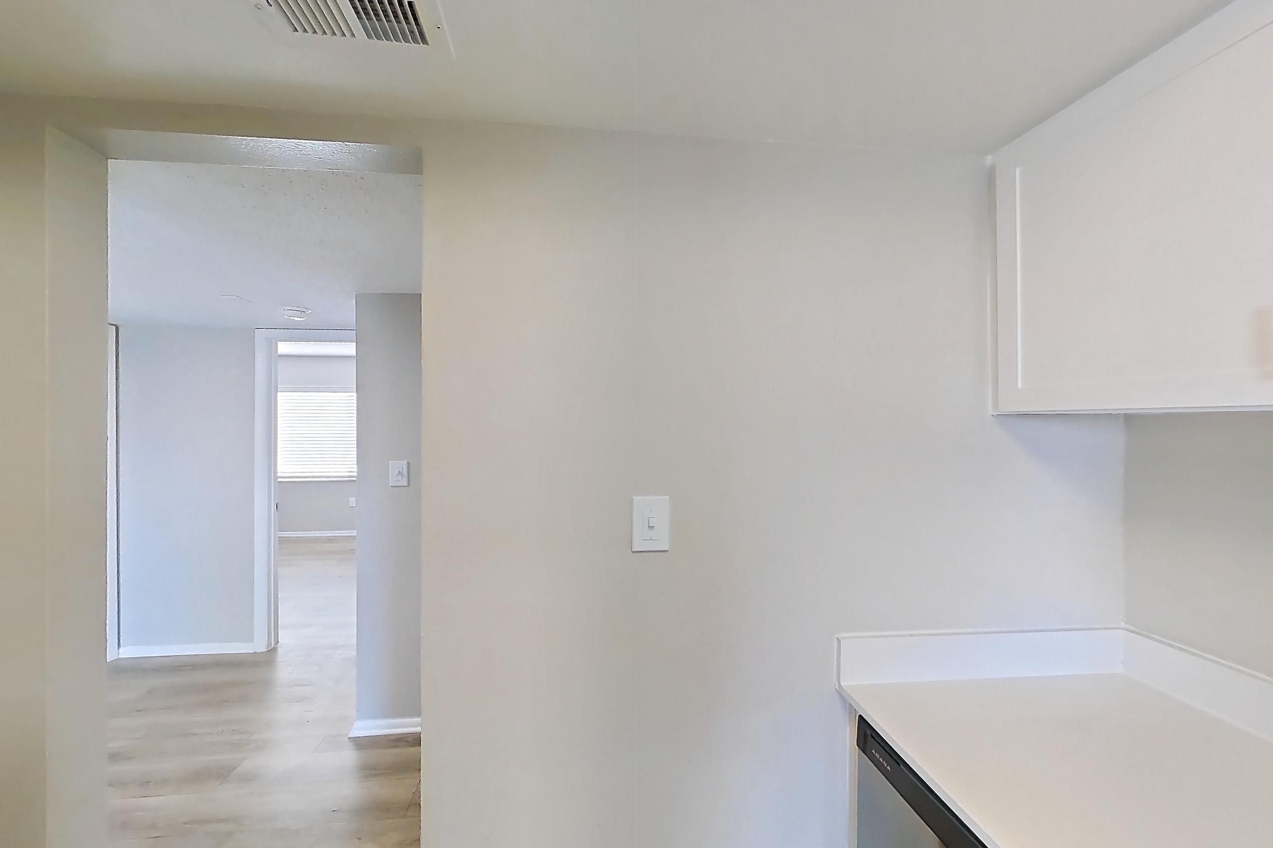 Kitchen with dishwasher, electric range, light countertops, light wood-finish flooring, oven/range, range hood, refrigerator, and stainless steel appliances, Apartment 172 at Venue at Winter Park
