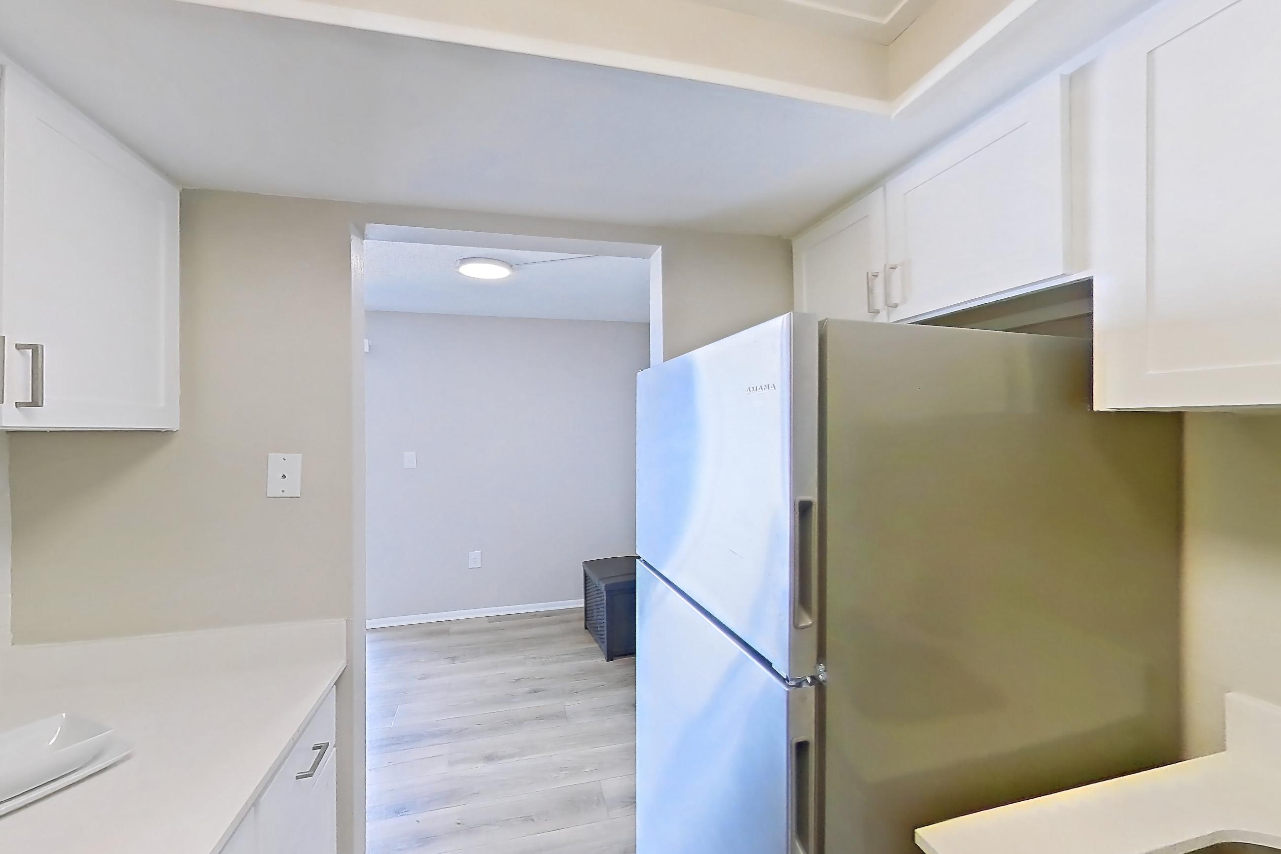 Kitchen with electric range, light countertops, light wood-finish flooring, oven/range, refrigerator, stainless steel appliances, and white appliances, Apartment 178 at Venue at Winter Park