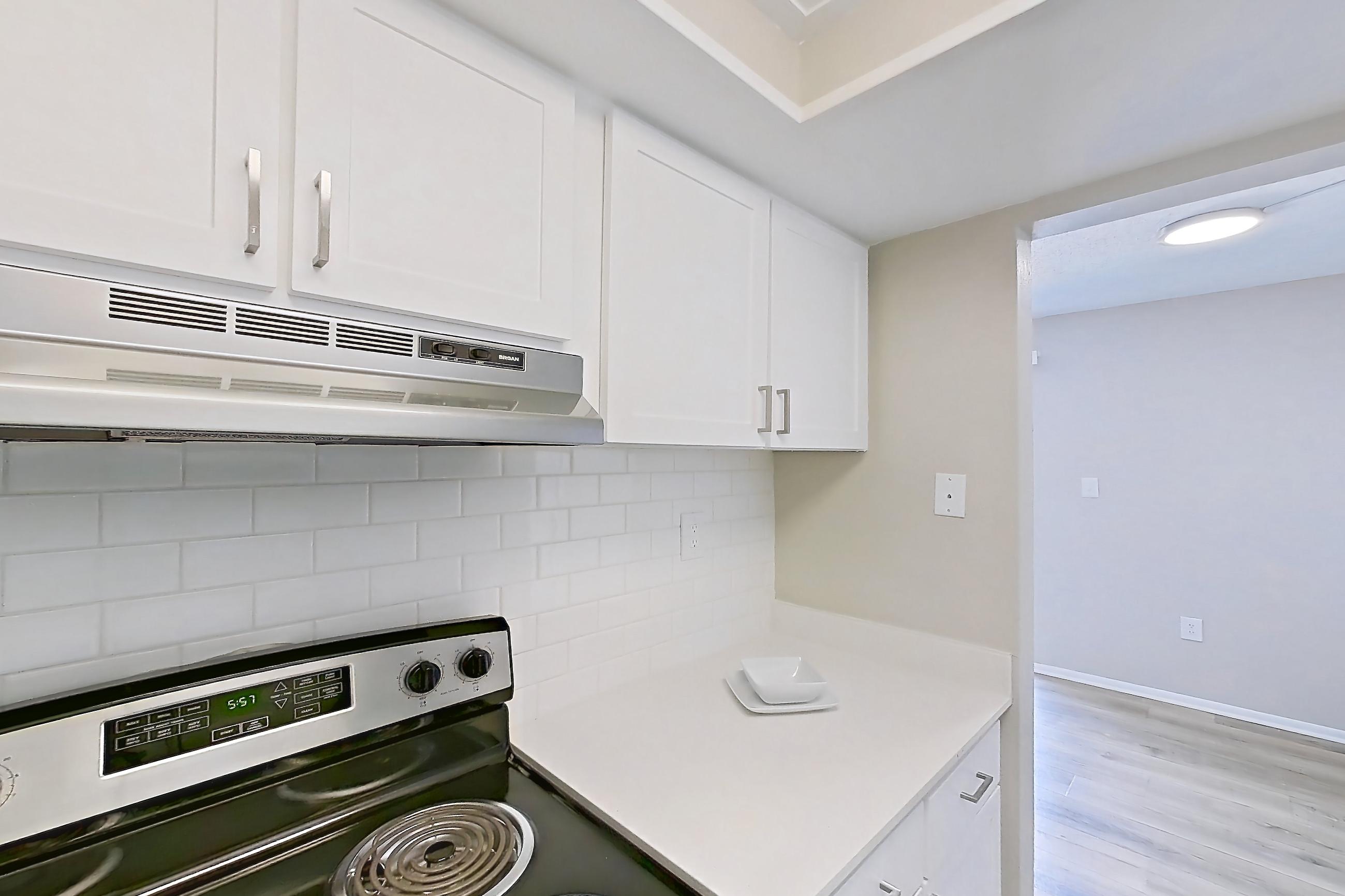 Kitchen with electric range, light countertops, light wood-finish flooring, oven/range, refrigerator, stainless steel appliances, and white appliances, Apartment 178 at Venue at Winter Park