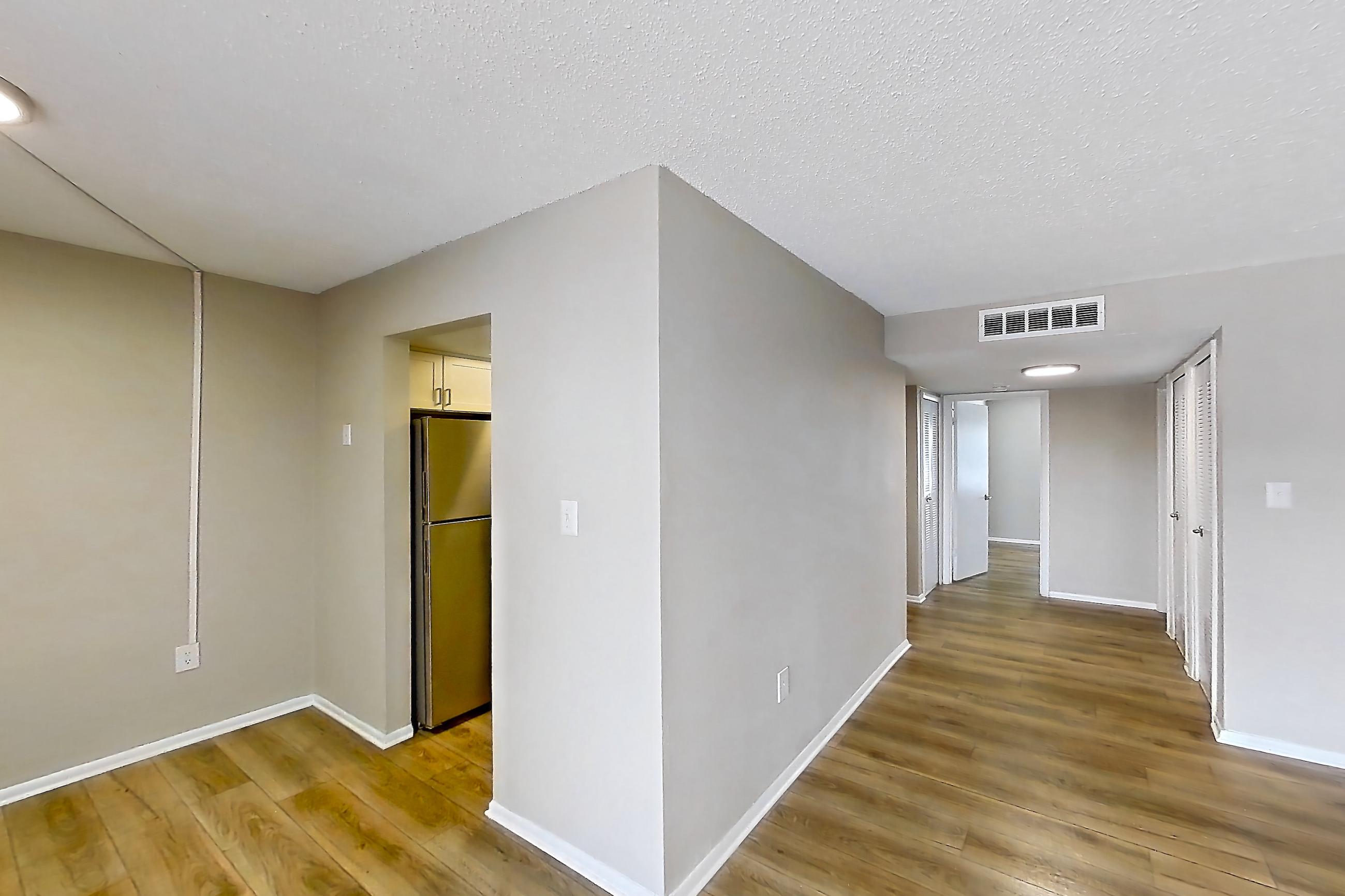 Living room with light wood-finish flooring and refrigerator, Apartment 178 at Venue at Winter Park