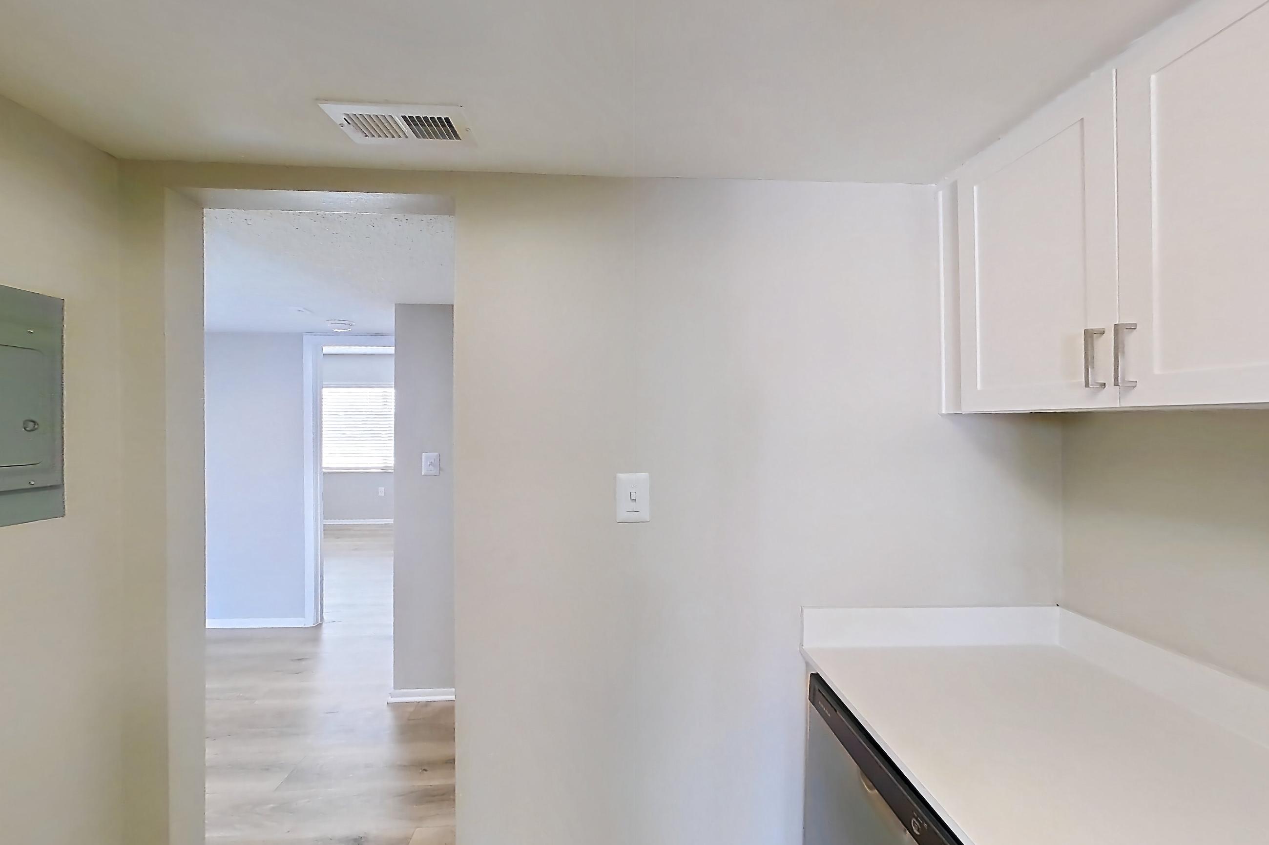 Kitchen with black appliances, dishwasher, electric range, light countertops, light wood-finish flooring, oven/range, range hood, and stainless steel appliances, Apartment 232 at Venue at Winter Park