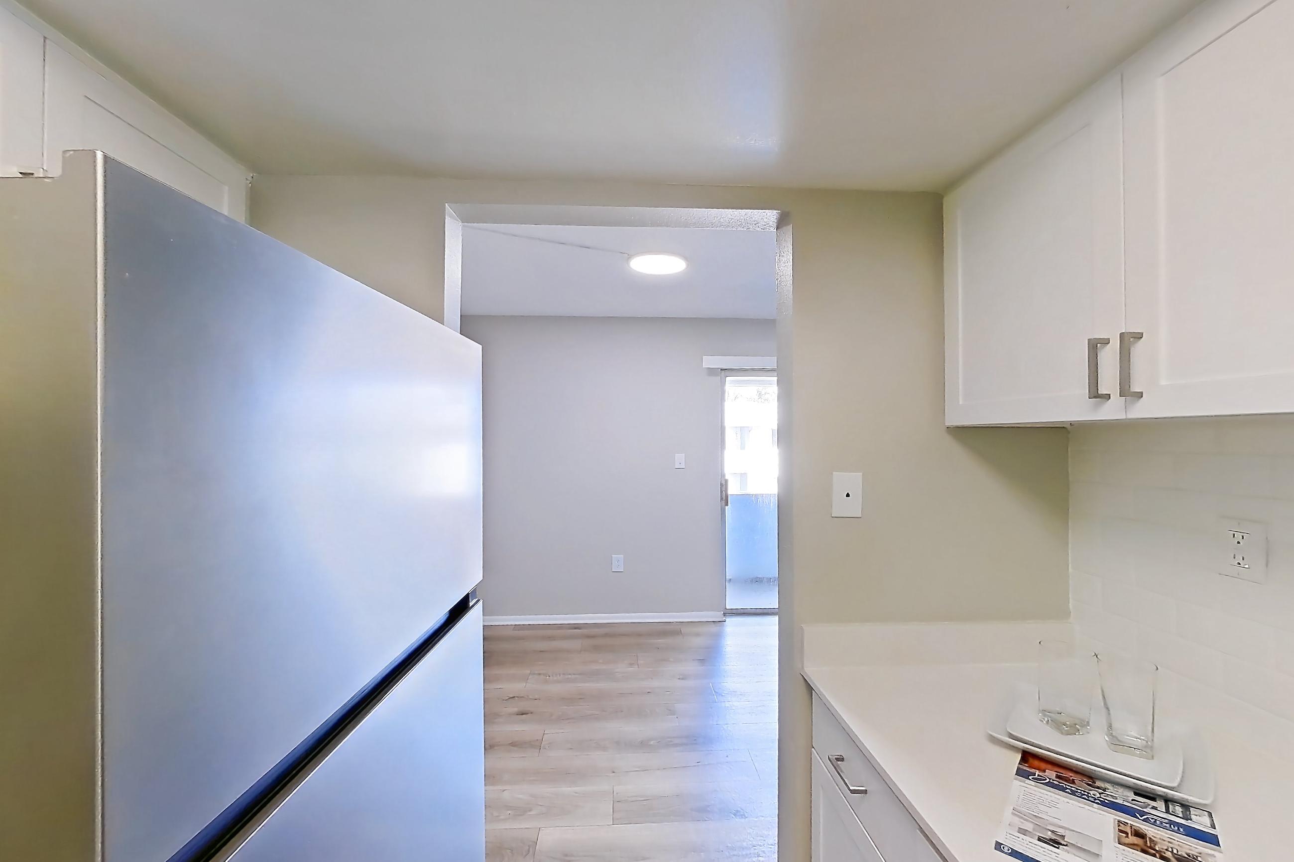 Kitchen with black appliances, dishwasher, electric range, light countertops, light wood-finish flooring, oven/range, range hood, and stainless steel appliances, Apartment 232 at Venue at Winter Park