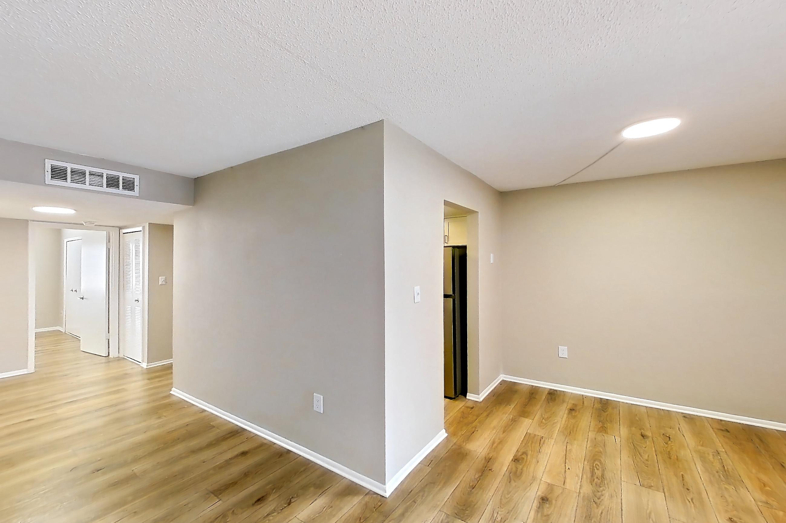 Living room with light wood-finish flooring, refrigerator, stainless steel appliances, and wood-finish flooring, Apartment 232 at Venue at Winter Park
