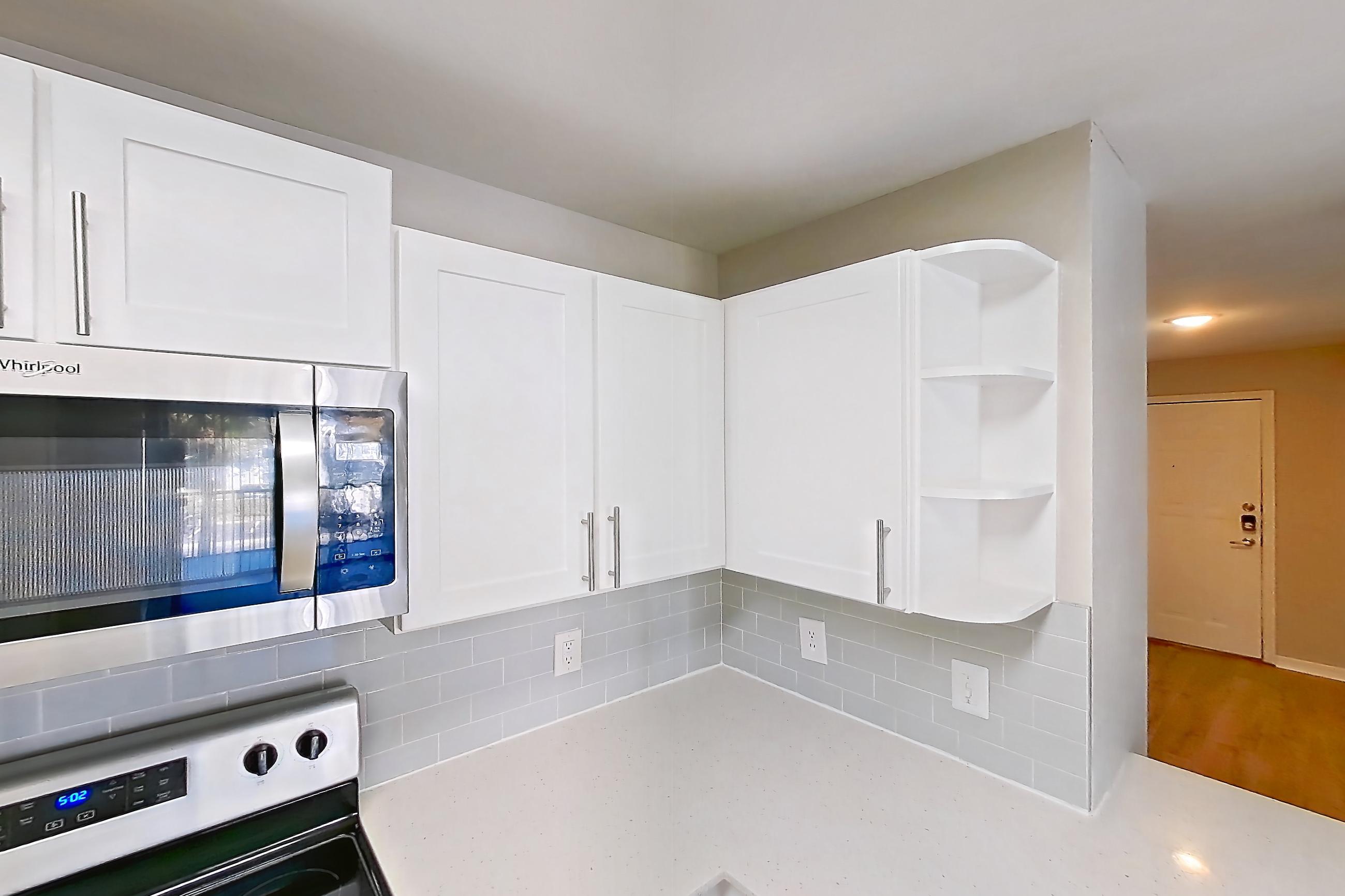 Kitchen with dishwasher, electric range, light countertops, light stone countertops, light wood-finish flooring, microwave, oven/range, refrigerator, and stainless steel appliances, Apartment 09-201 at Boot Ranch