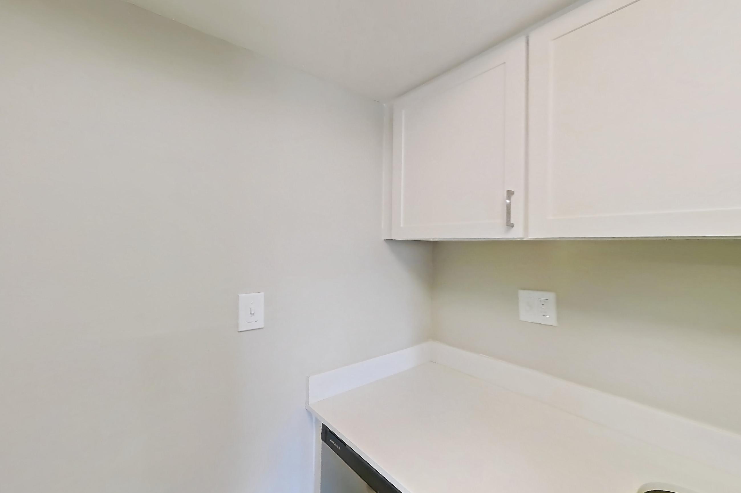 Kitchen with black appliances, dishwasher, electric range, light countertops, light wood-finish flooring, oven/range, range hood, refrigerator, stainless steel appliances, and white appliances, Apartment 315 at Venue at Winter Park
