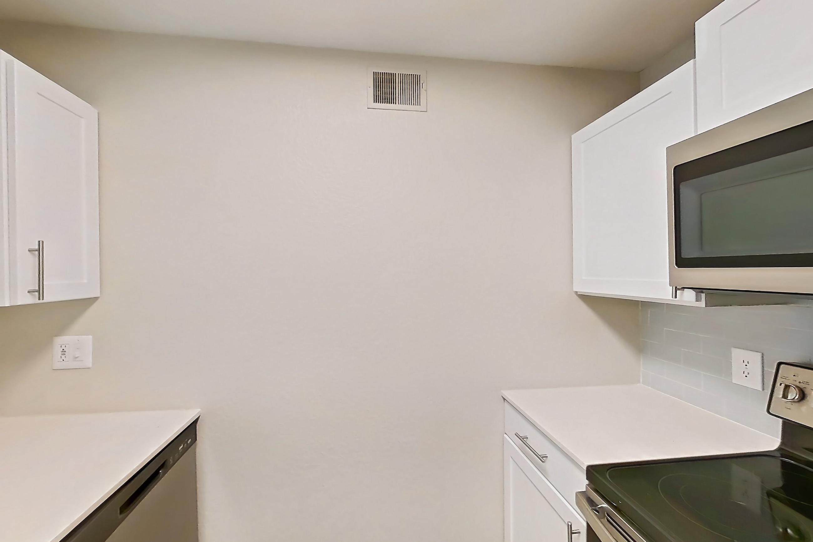 Kitchen with dishwasher, electric range, light countertops, light wood-finish flooring, microwave, oven/range, refrigerator, and stainless steel appliances, Apartment 15-105 at Boot Ranch