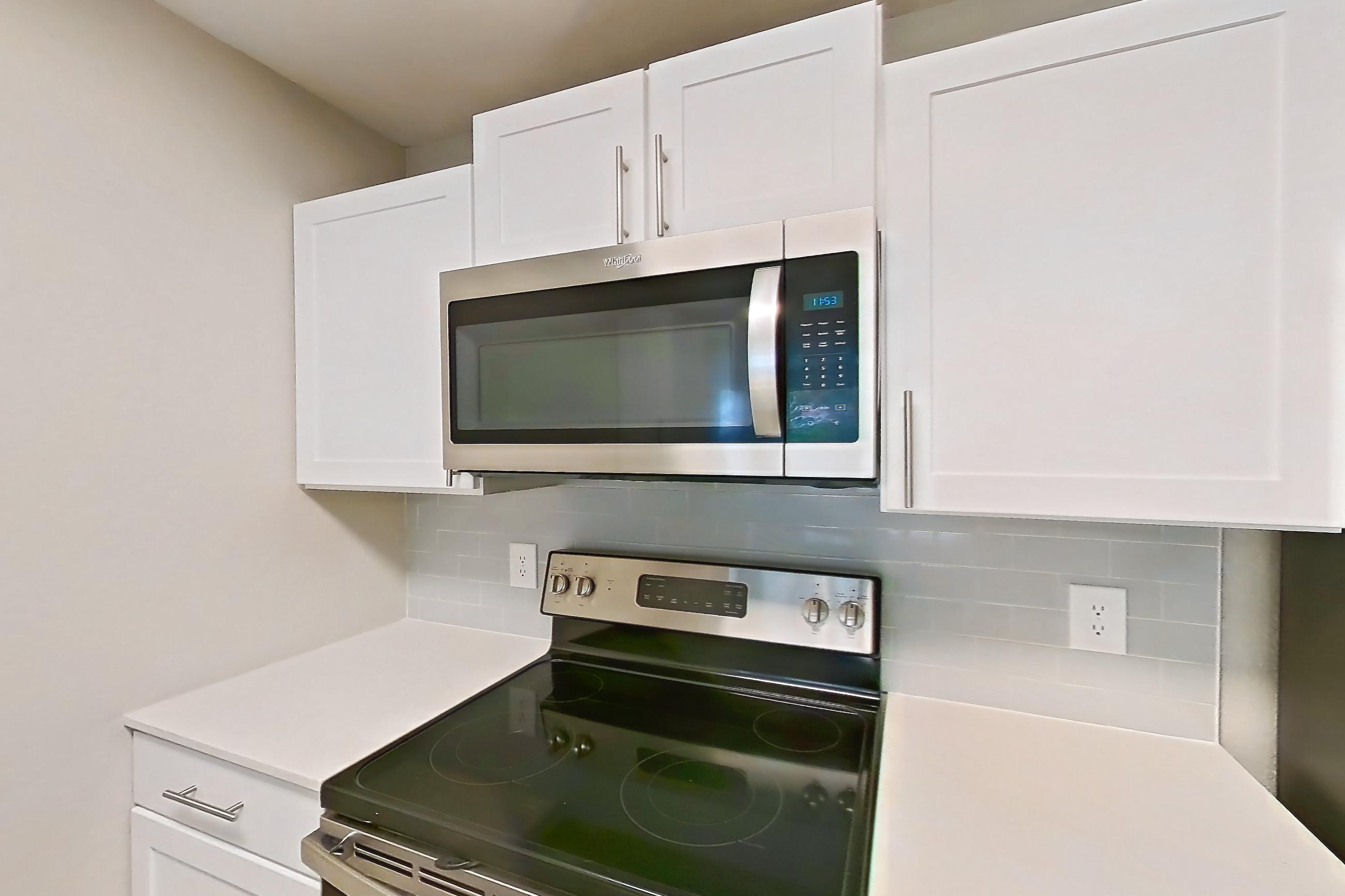Kitchen with dishwasher, electric range, light countertops, light wood-finish flooring, microwave, oven/range, refrigerator, and stainless steel appliances, Apartment 15-105 at Boot Ranch